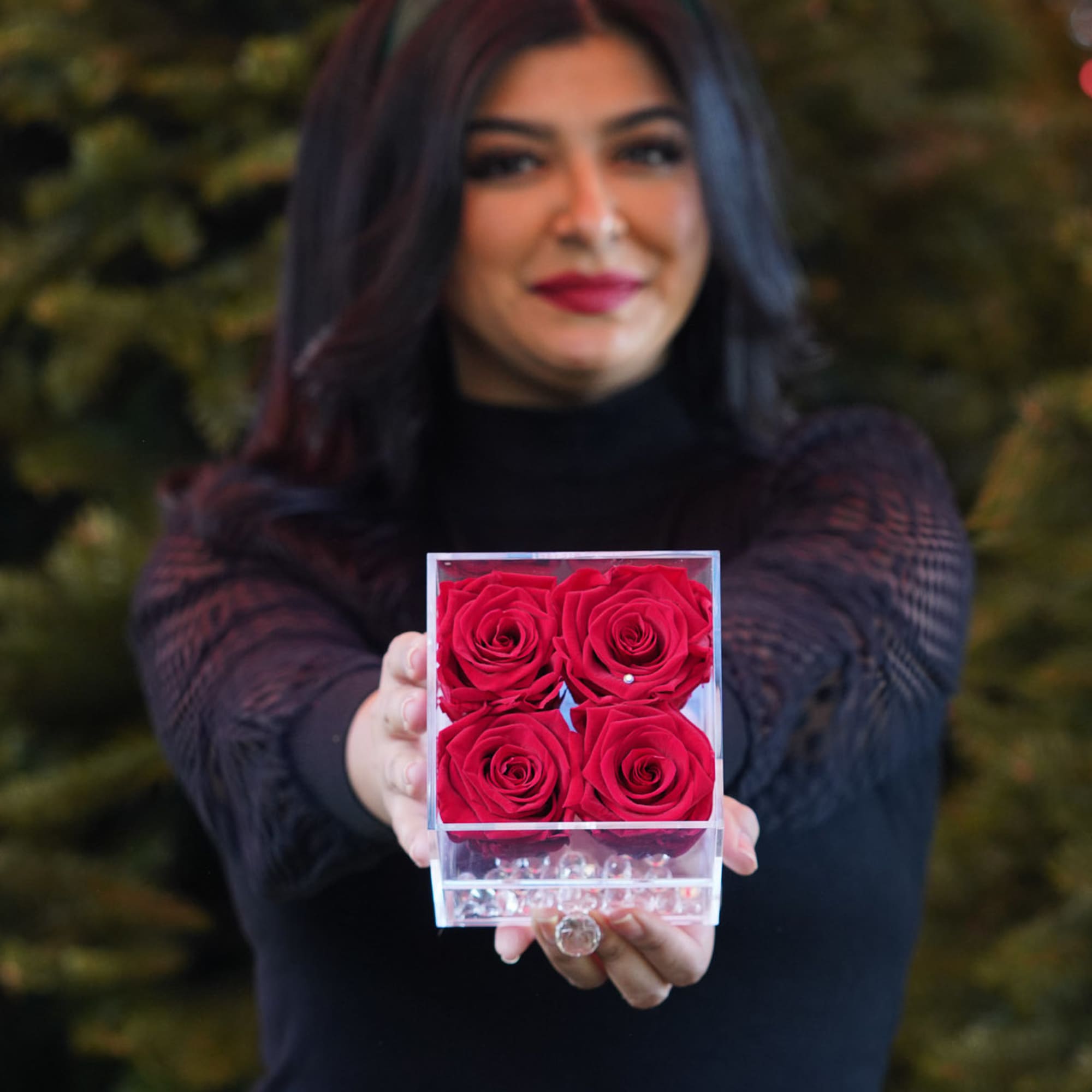 Woman holding a clear box of four red roses