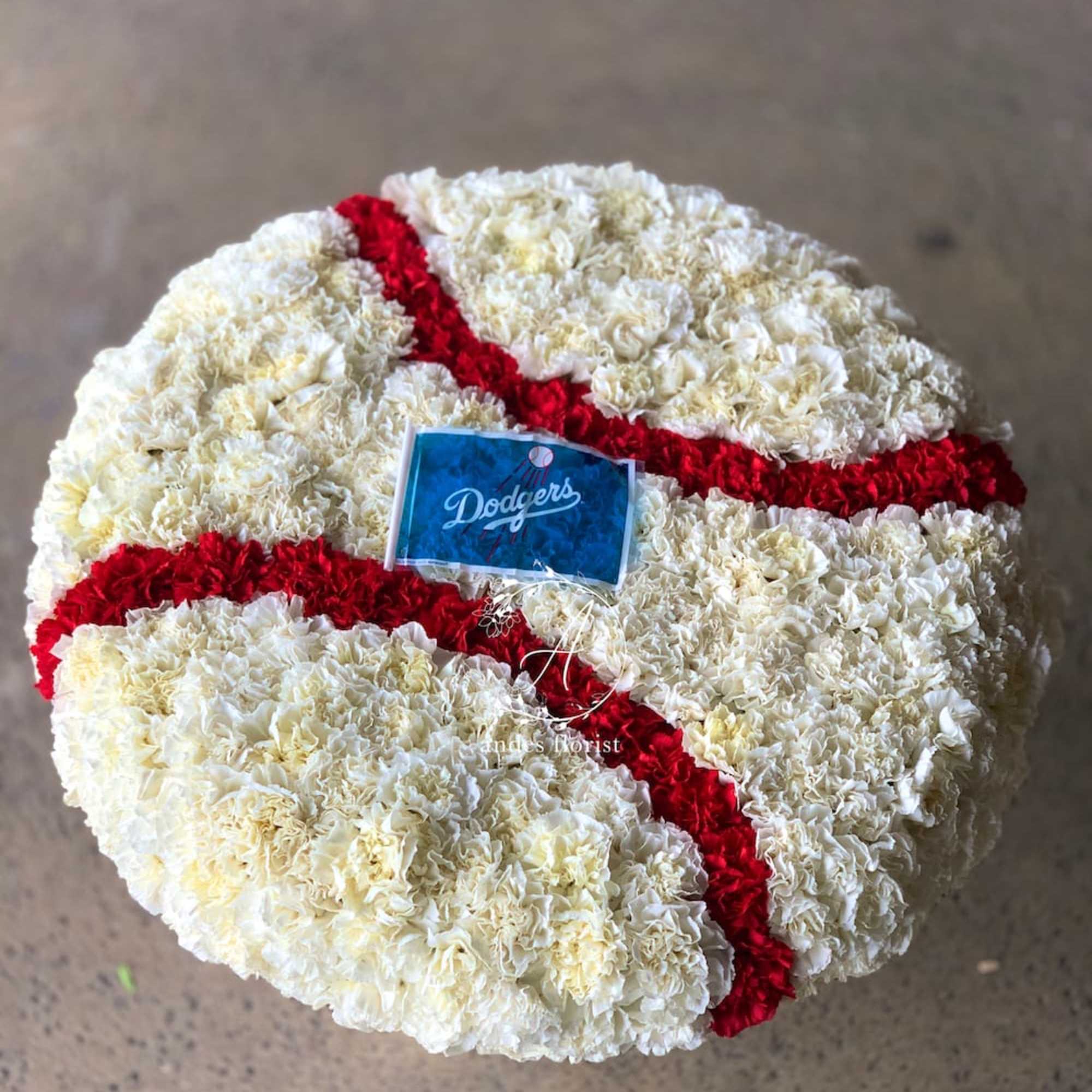 Baseball-shaped floral arrangement in white and red carnations with a Dodgers flag