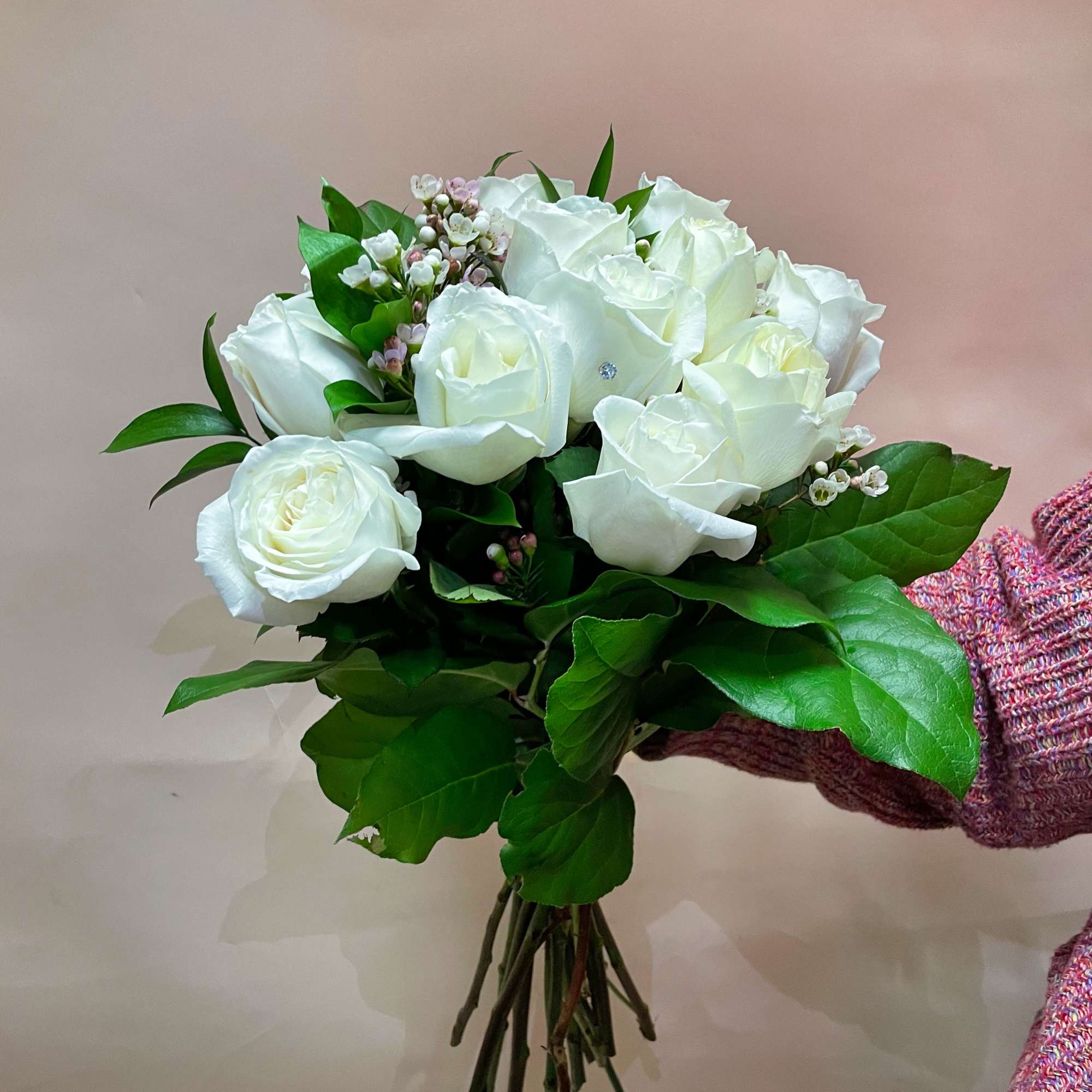 Hand-tied bouquet of white roses with greenery