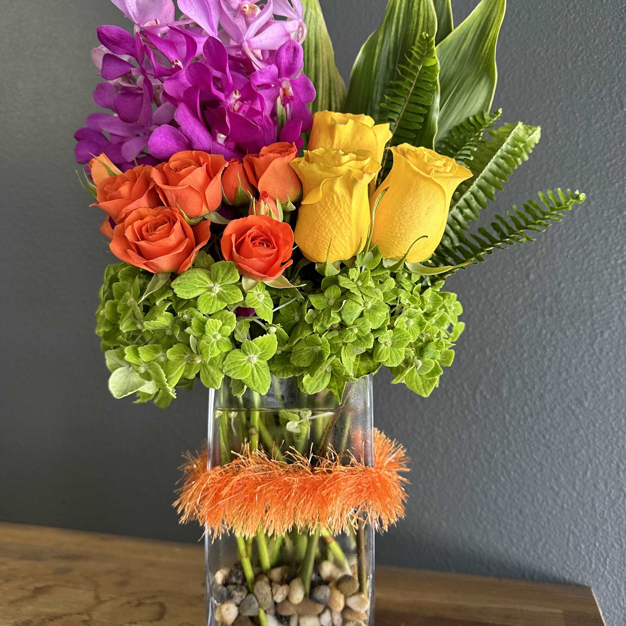 Colorful bouquet of orchids and roses in a glass vase
