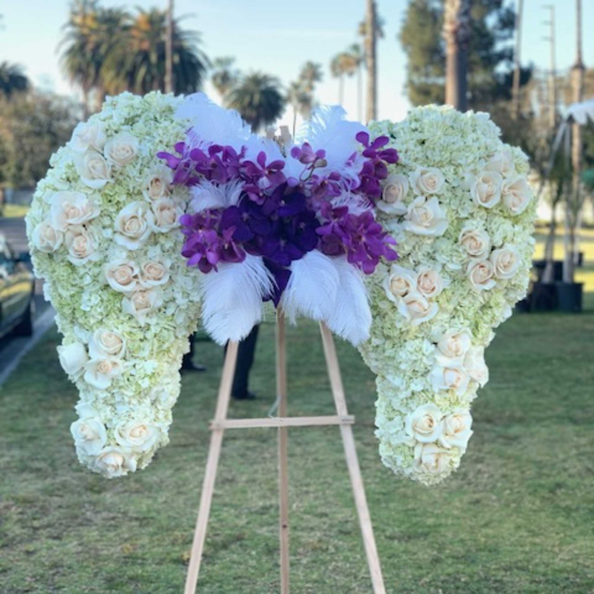 Large floral heart on an easel with white roses and purple orchids