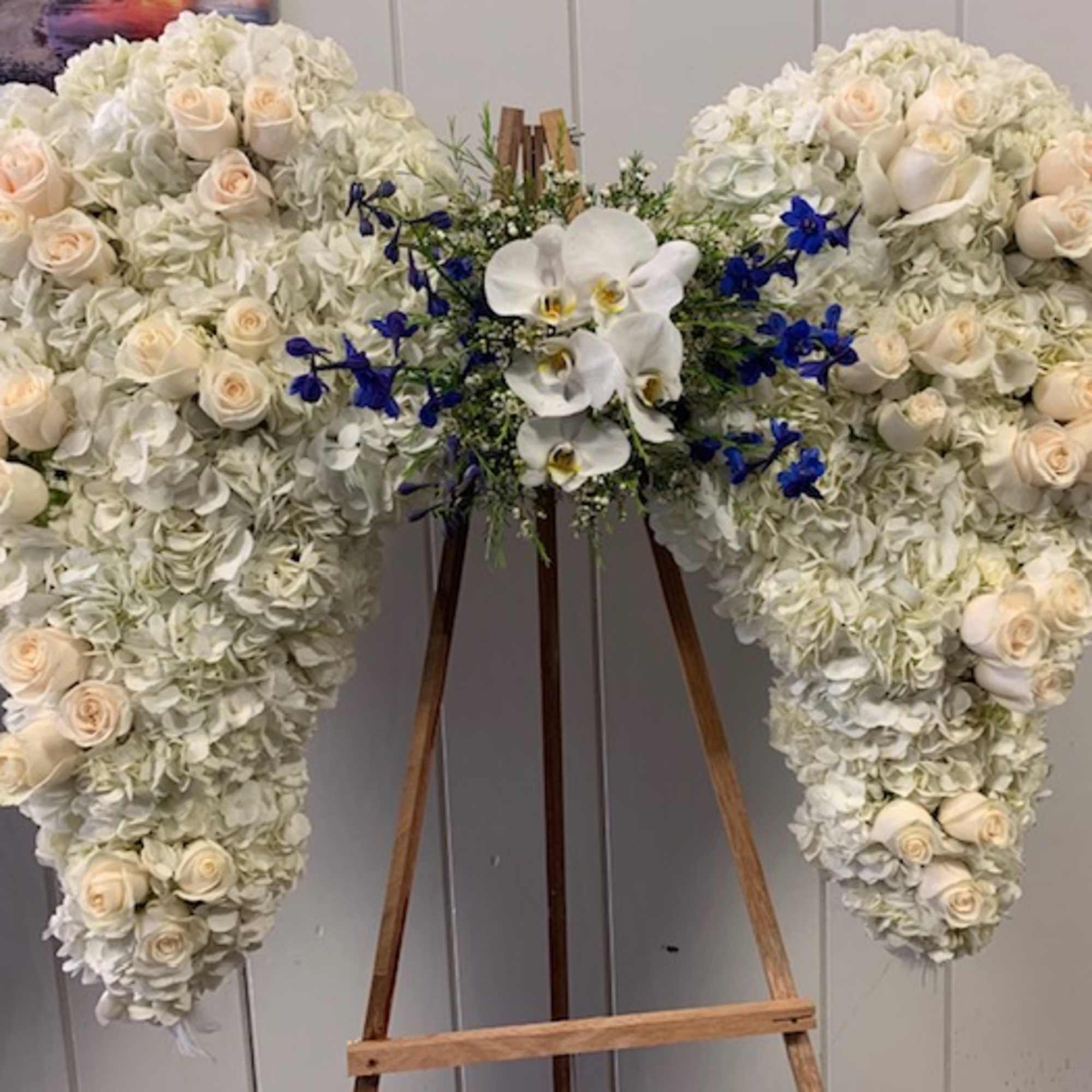 Large white floral heart on an easel with cream roses and blue accents