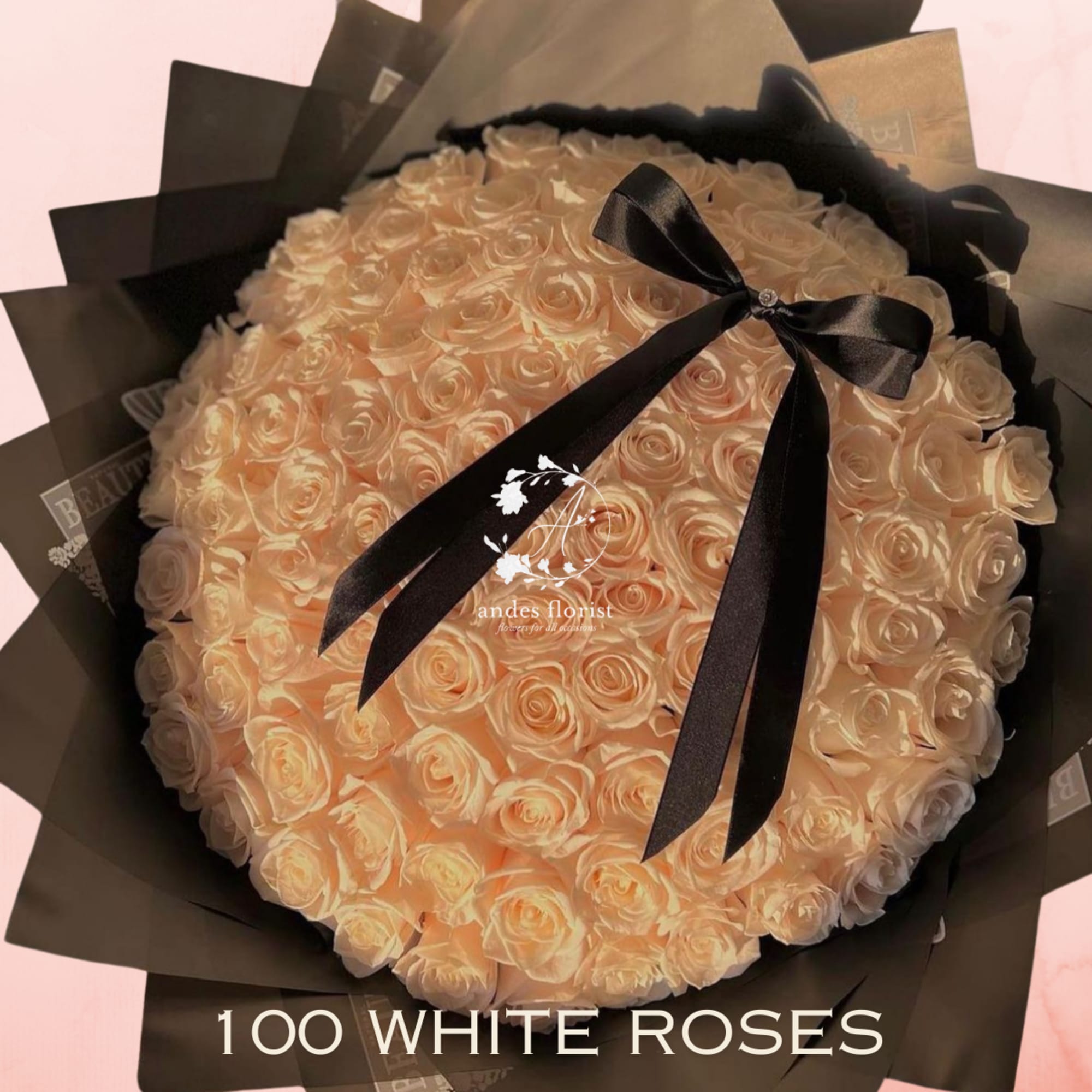 Large bouquet of white roses wrapped in black paper with a black ribbon