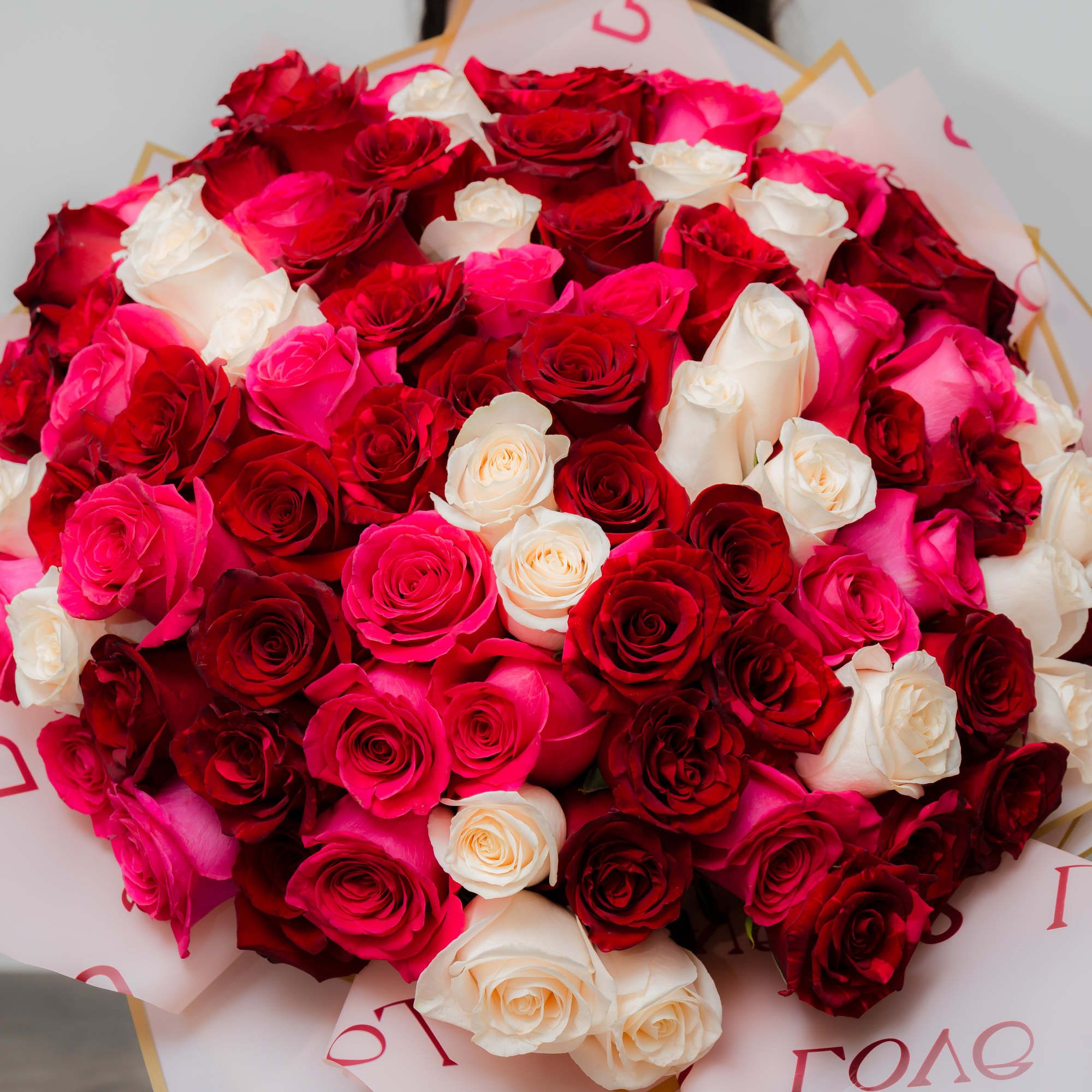 Large bouquet of red, pink, and white roses wrapped in printed paper, photo 3 of 10