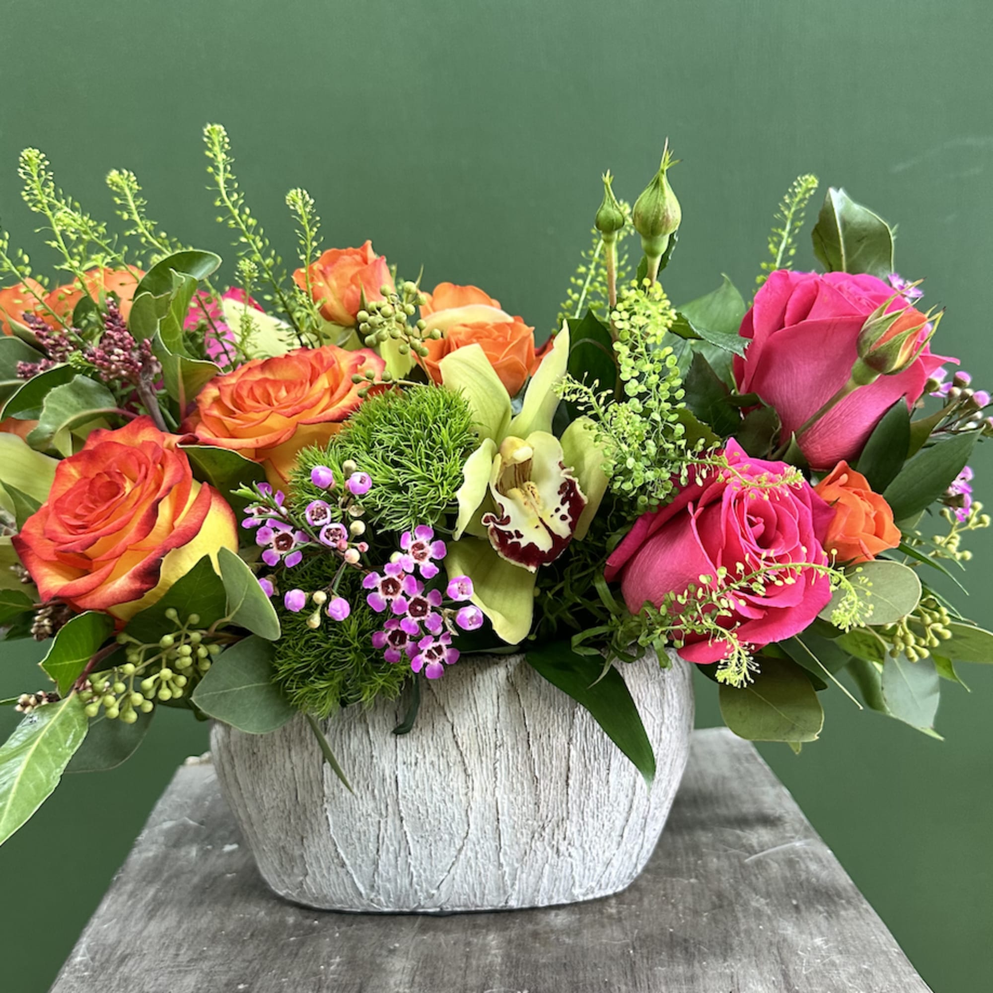 Mixed roses and orchids arranged in a white textured vase