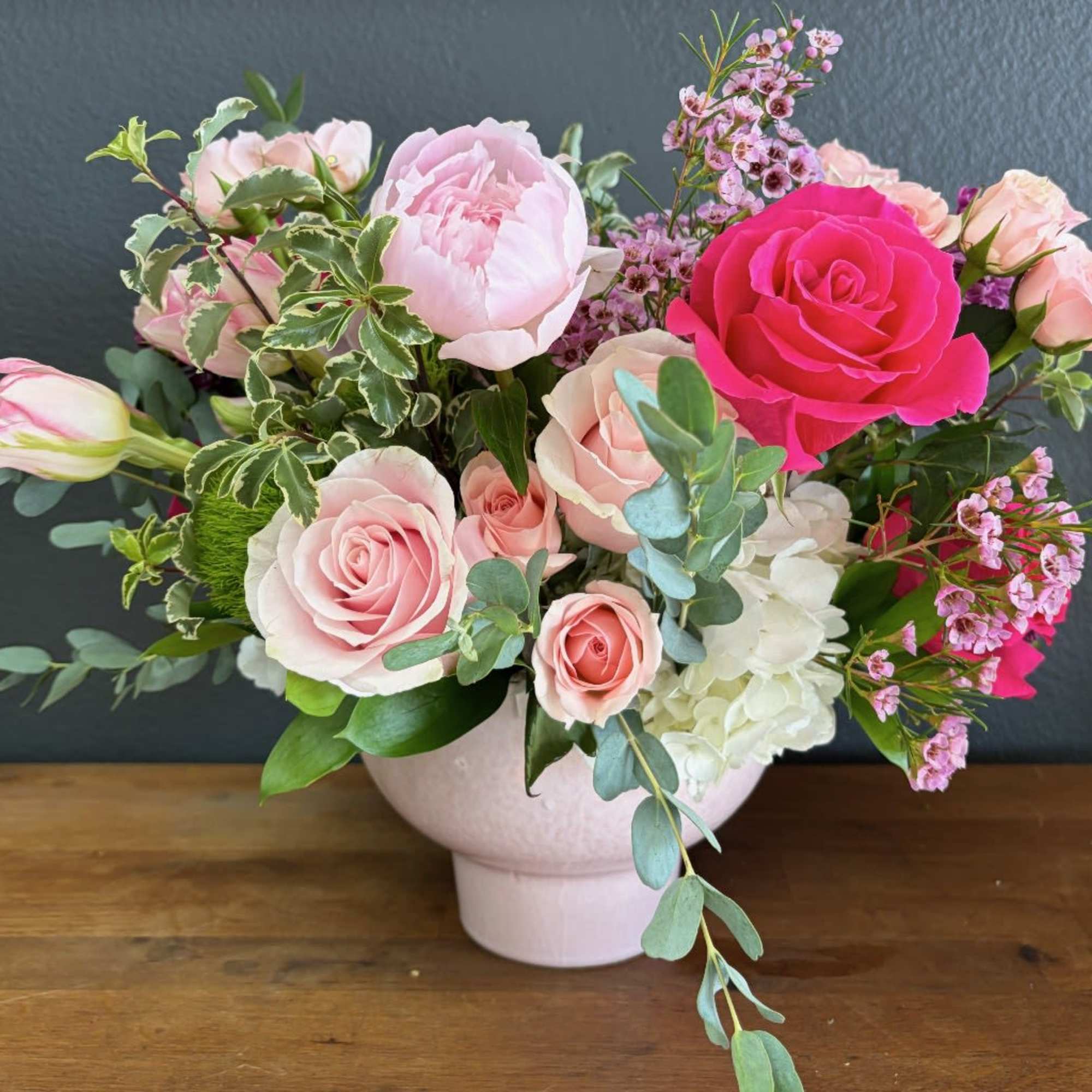 A romantic and artfully gathered arrangement in soft blush, ivory, and vibrant