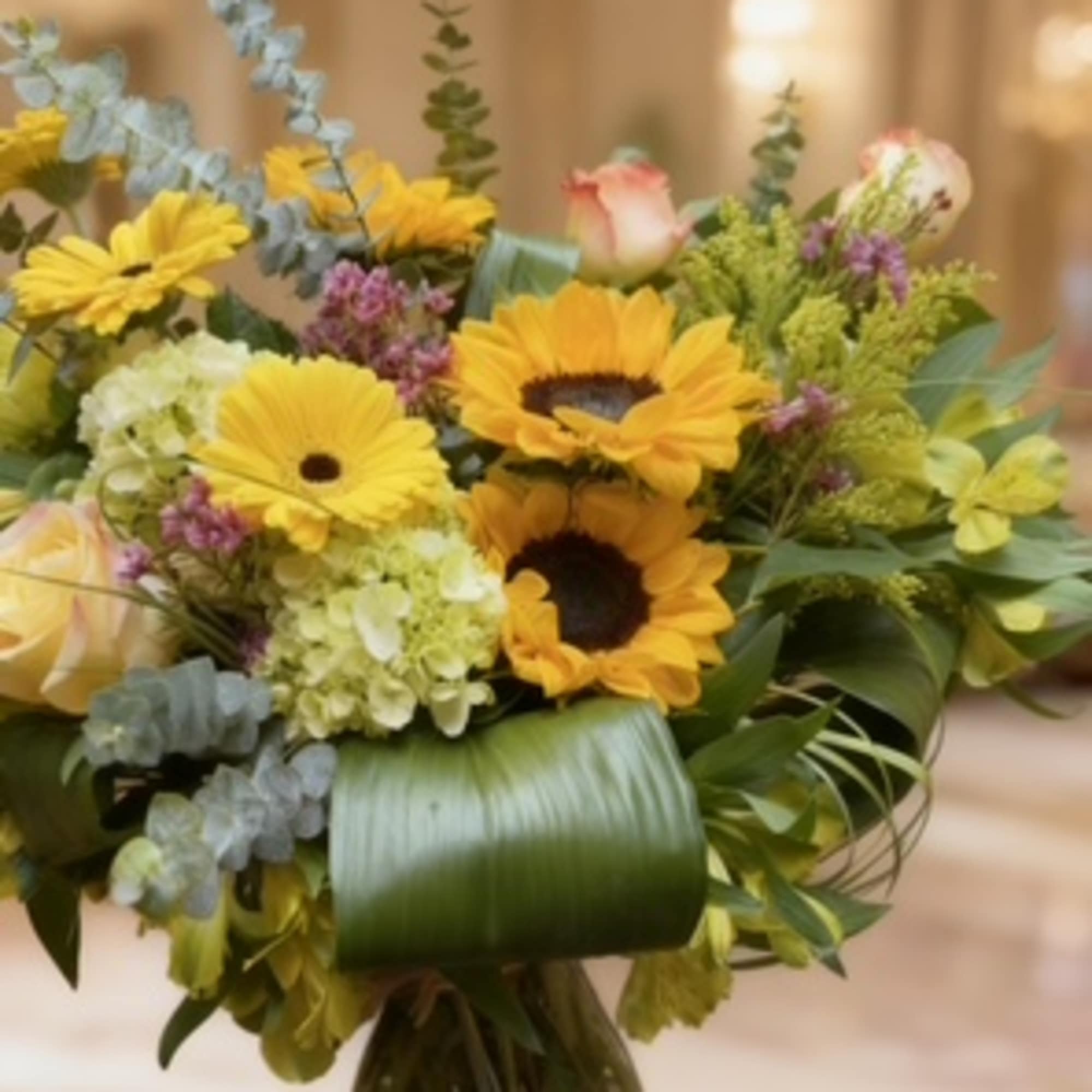 Bouquet of yellow sunflowers and pale roses in a glass vase