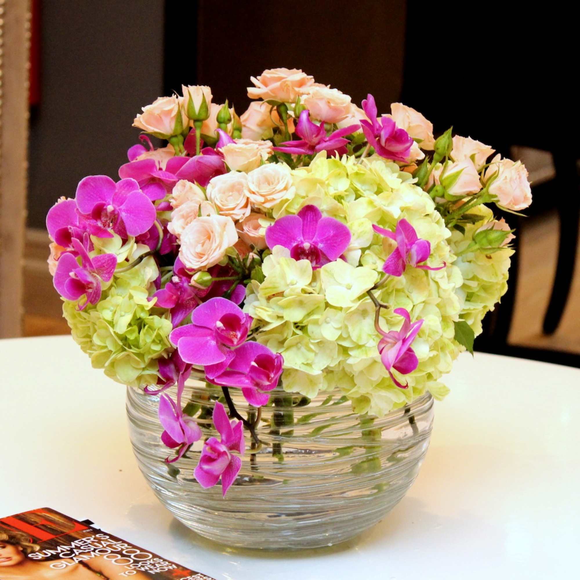 Bouquet of pink orchids and pale hydrangeas in a glass bowl vase