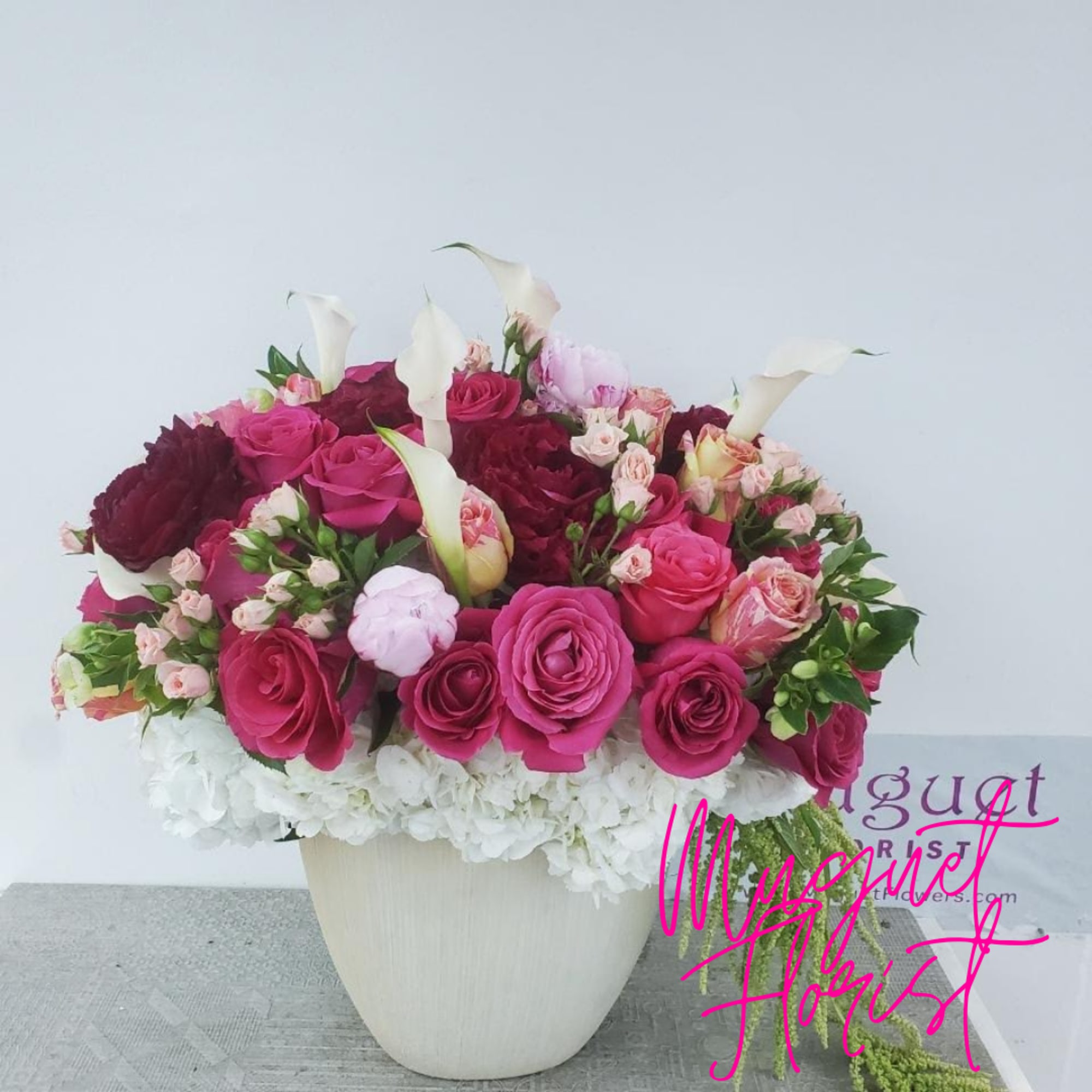 Pink and burgundy roses with white calla lilies in a white vase
