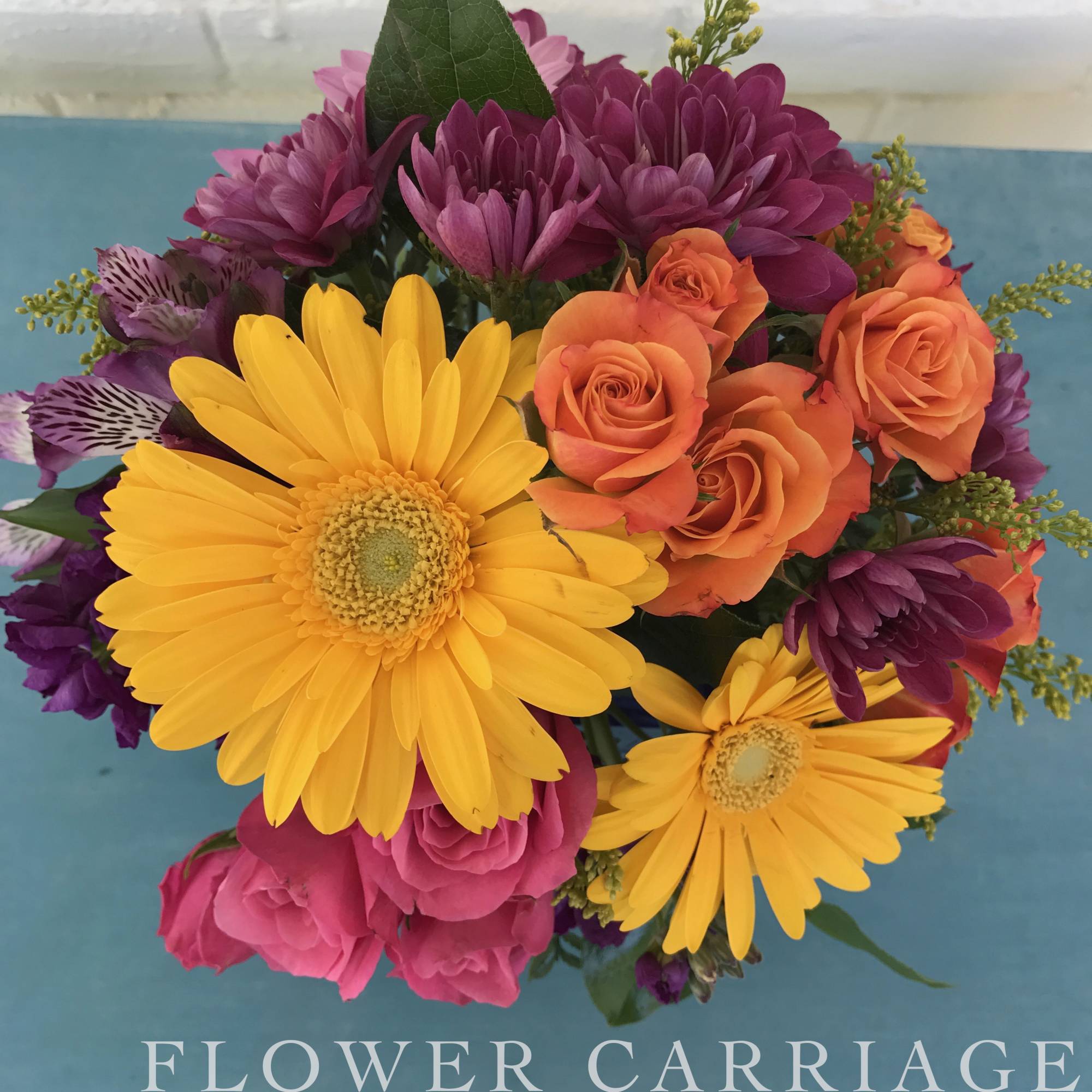 Bouquet of yellow gerbera daisies, orange roses, and purple flowers
