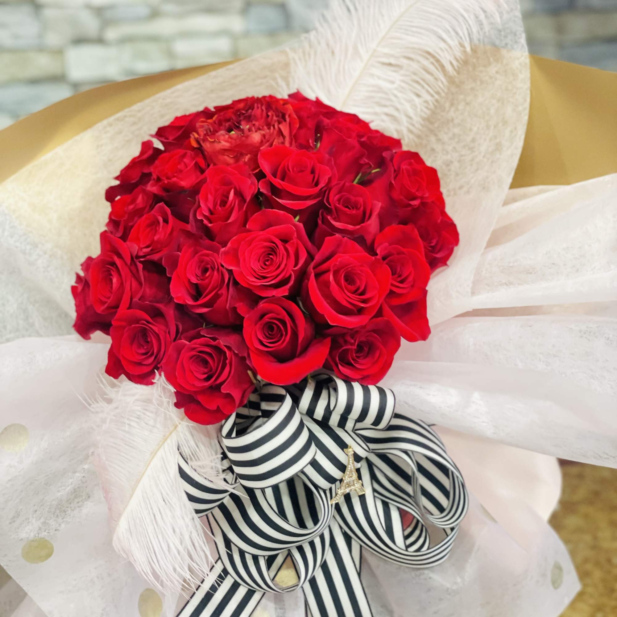 Bouquet of red roses wrapped in white paper with a striped ribbon, photo 2 of 2