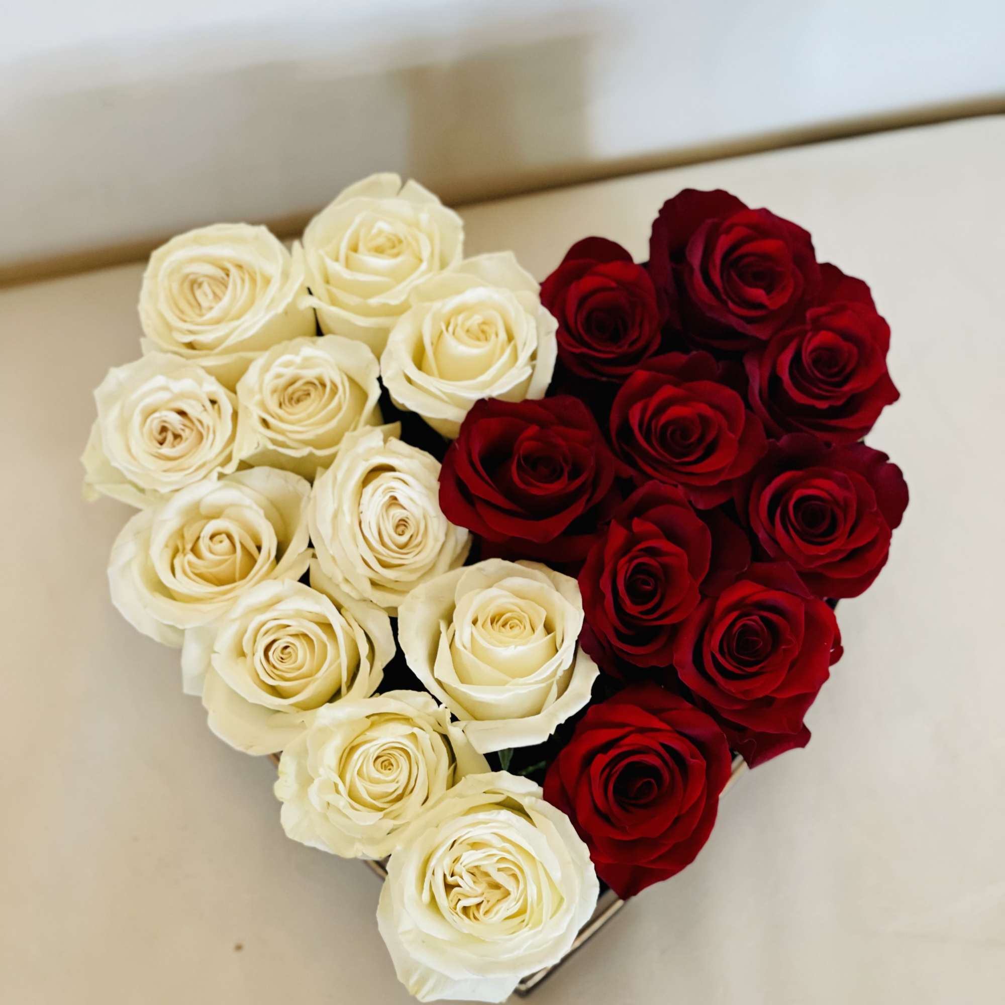 Heart-shaped arrangement of red and white roses in a box