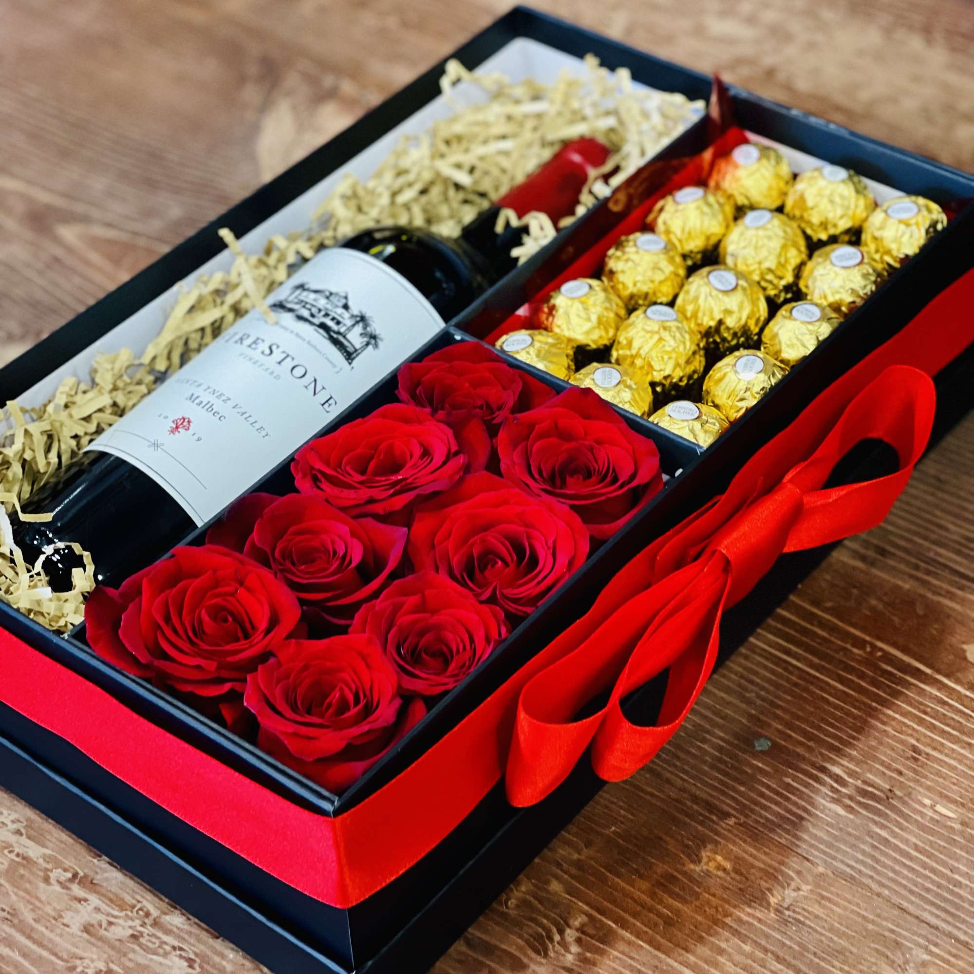 Gift box with red roses, chocolates, and a wine bottle