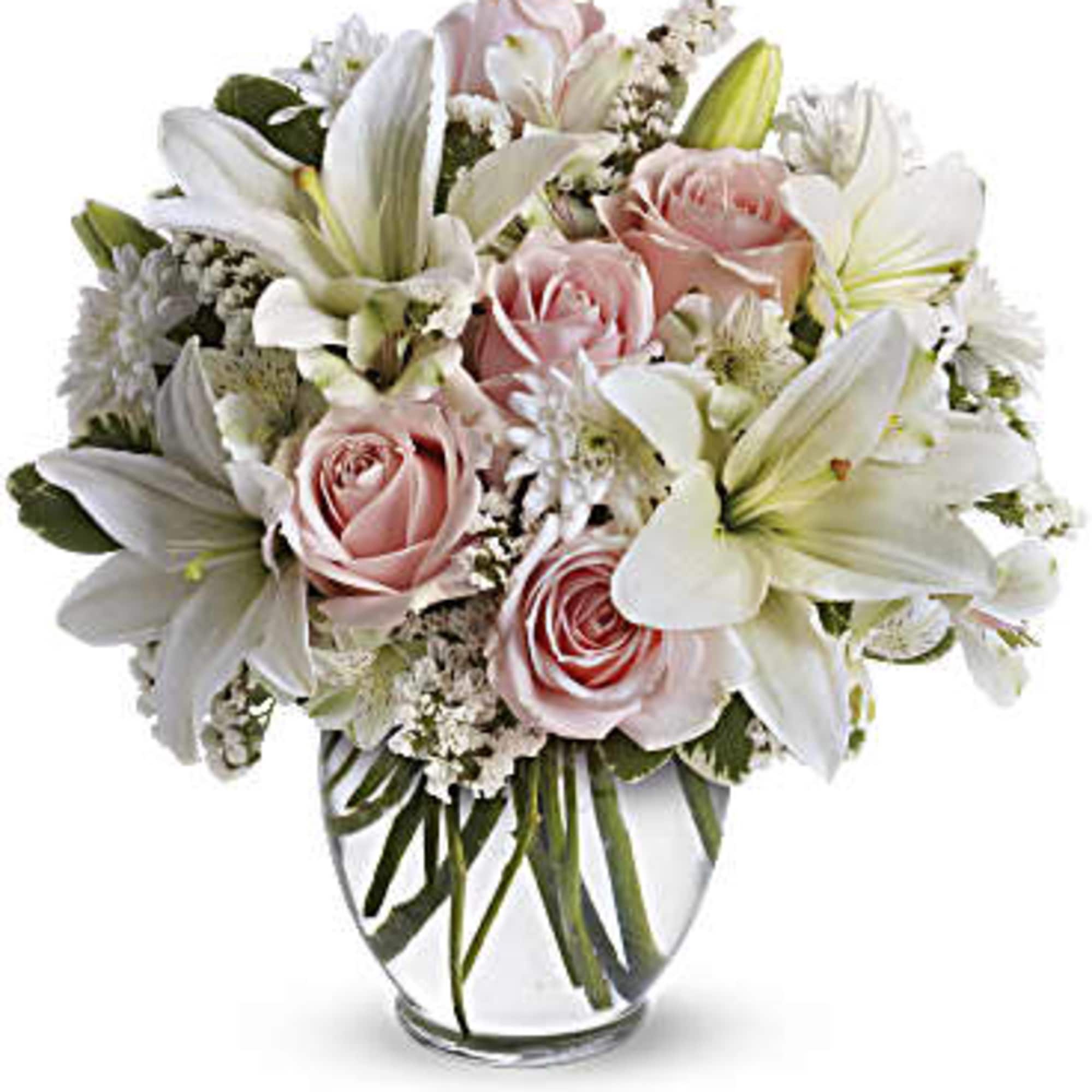Pink roses and white lilies arranged in a clear glass vase