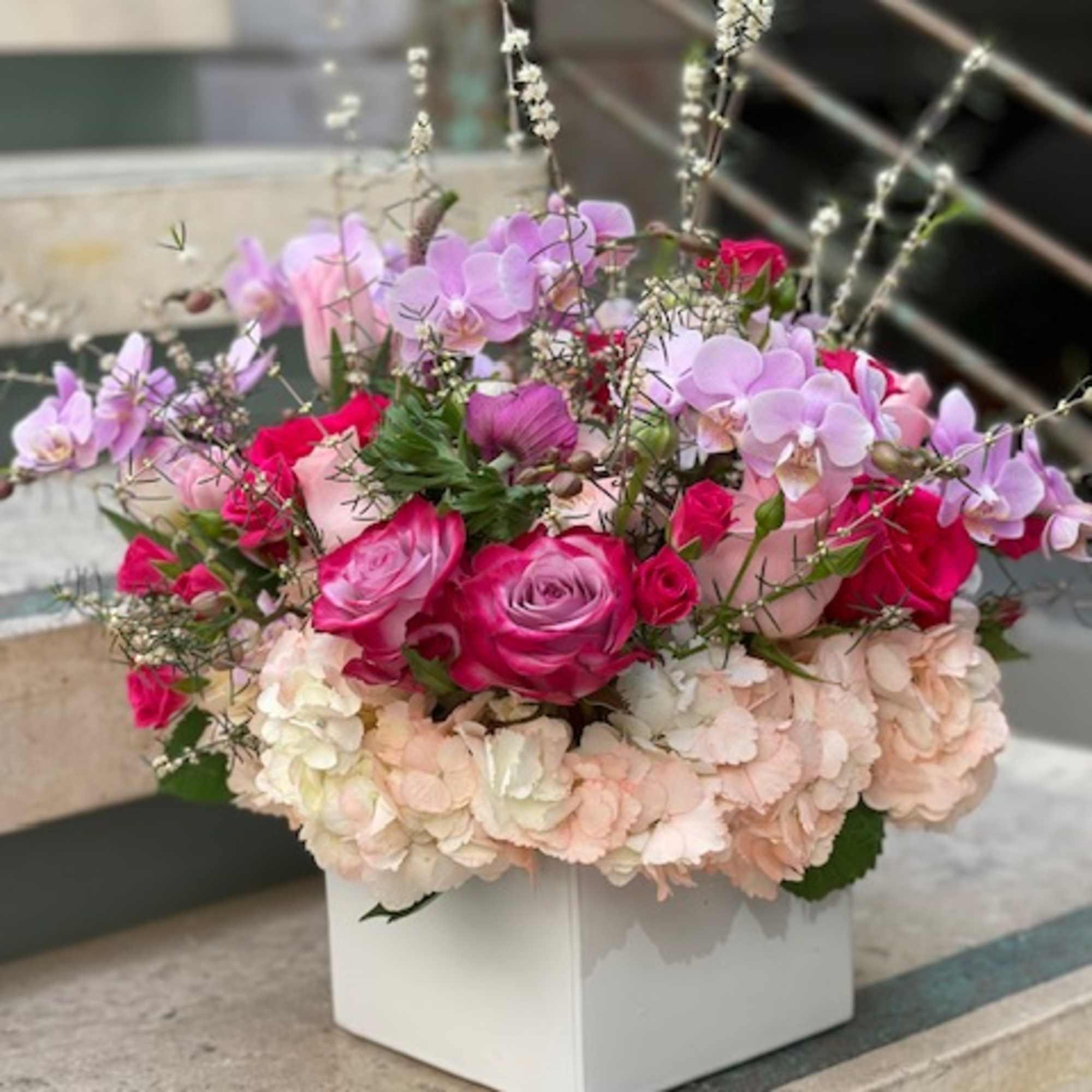 Pink and lavender floral arrangement in a white box