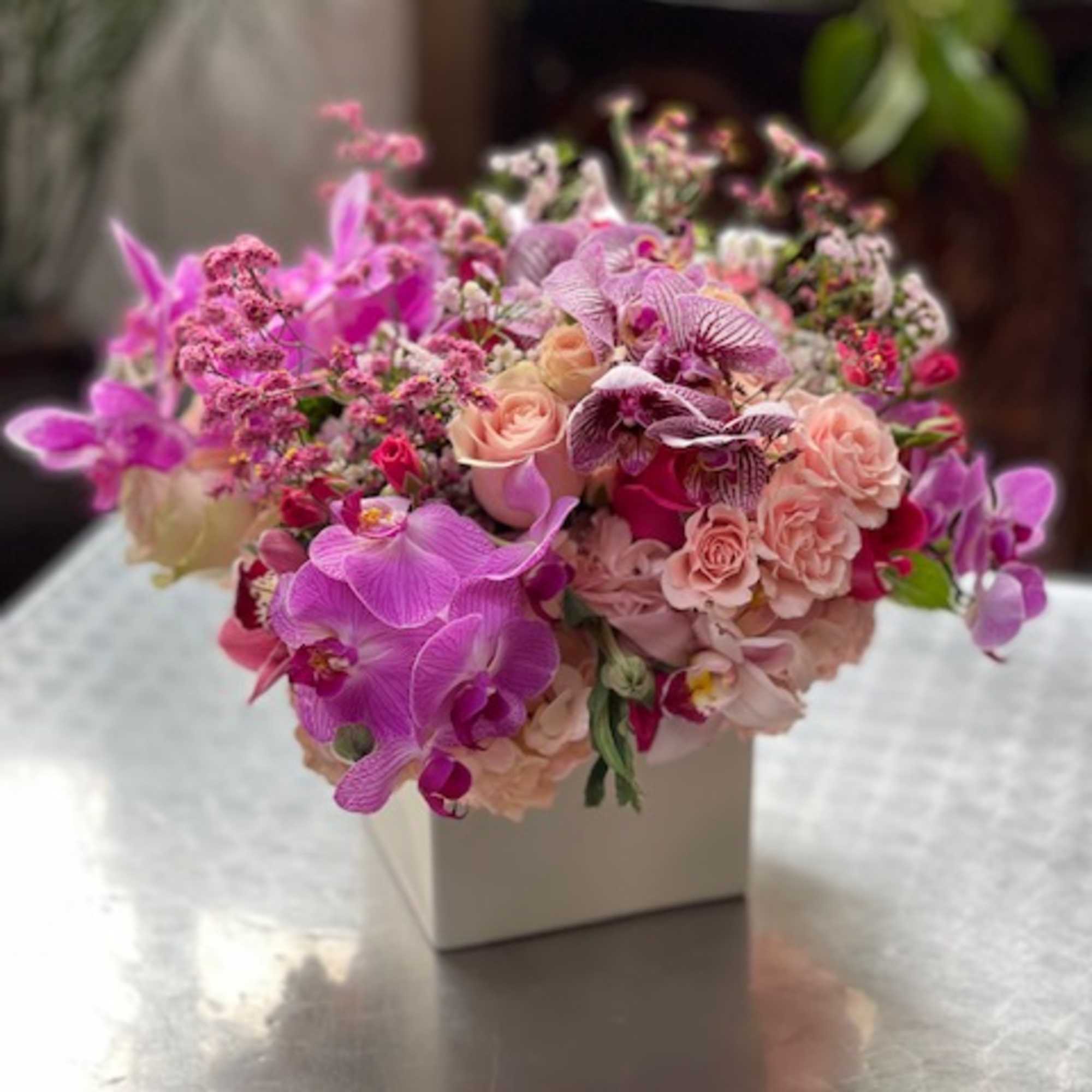 Pink and lavender bouquet in a white box vase