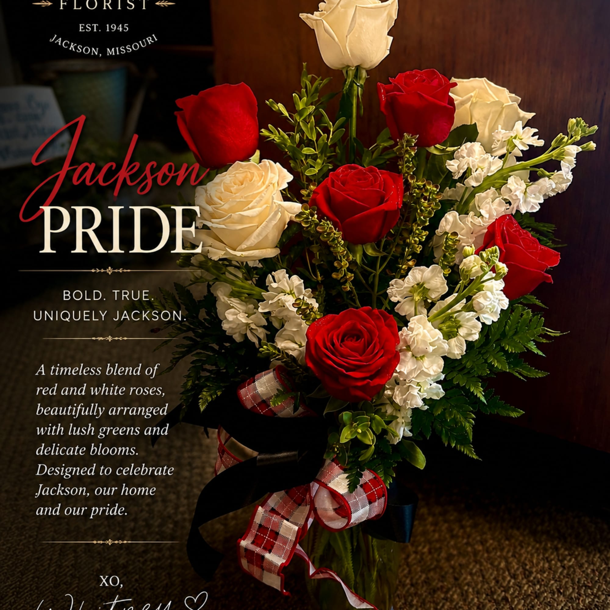 Red and white roses arranged in a glass vase with a plaid ribbon