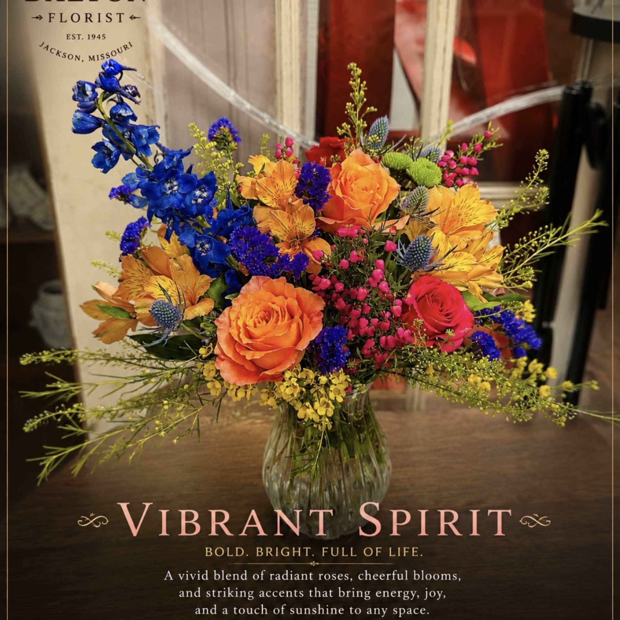 Bright mixed bouquet of roses and blue flowers in a glass vase