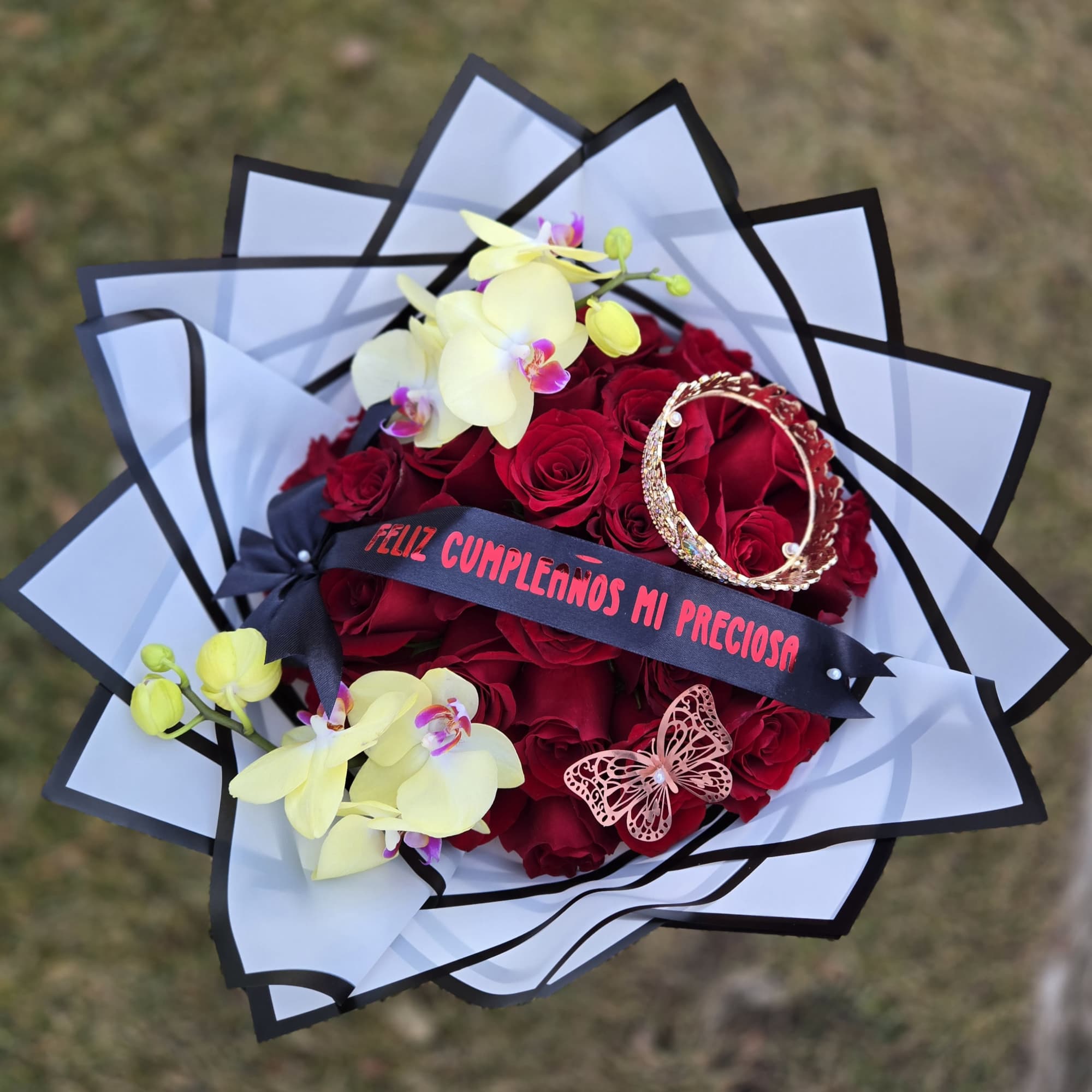 Bouquet of red roses with pale yellow orchids and a decorative ribbon