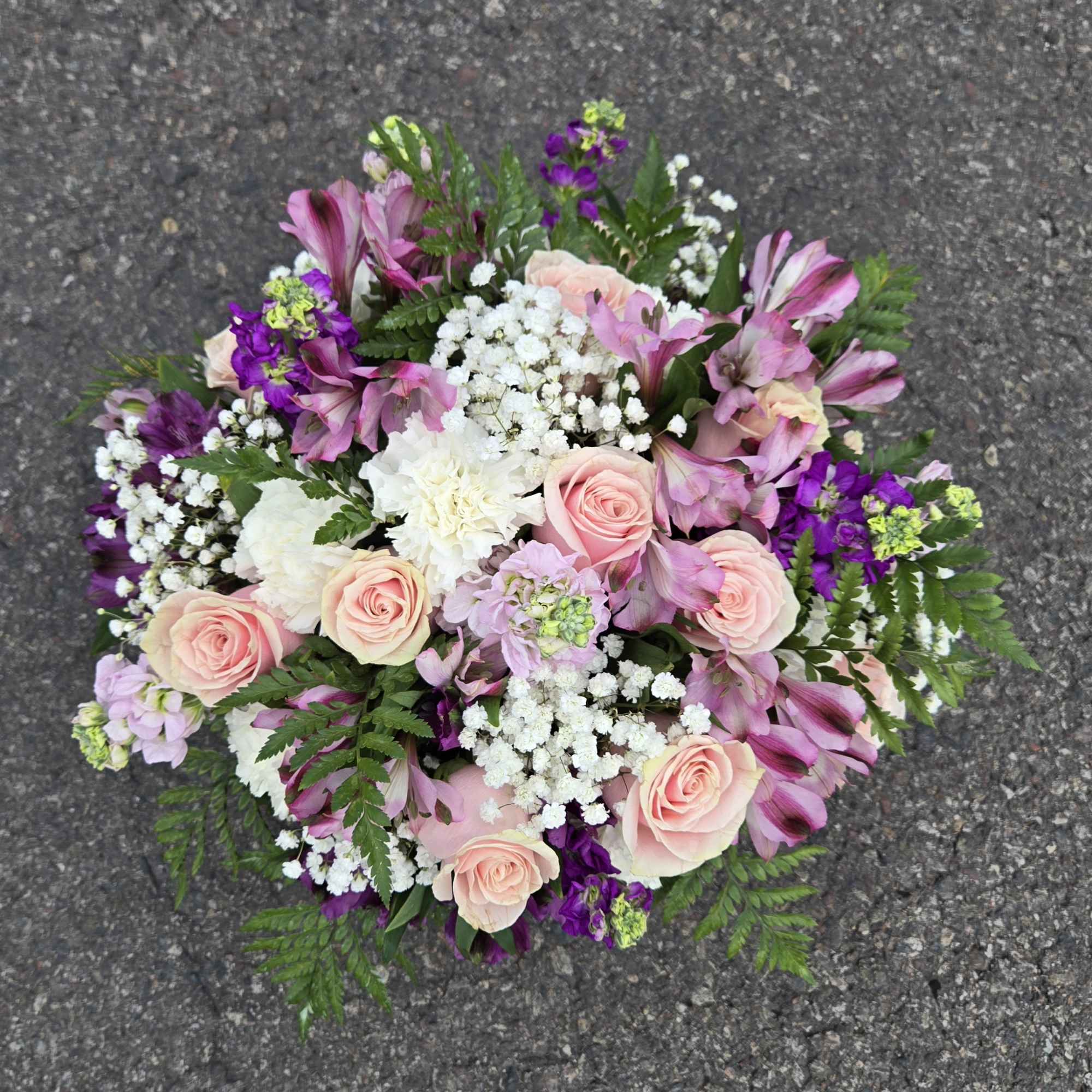 Pink roses and purple alstroemeria arranged in a round bouquet