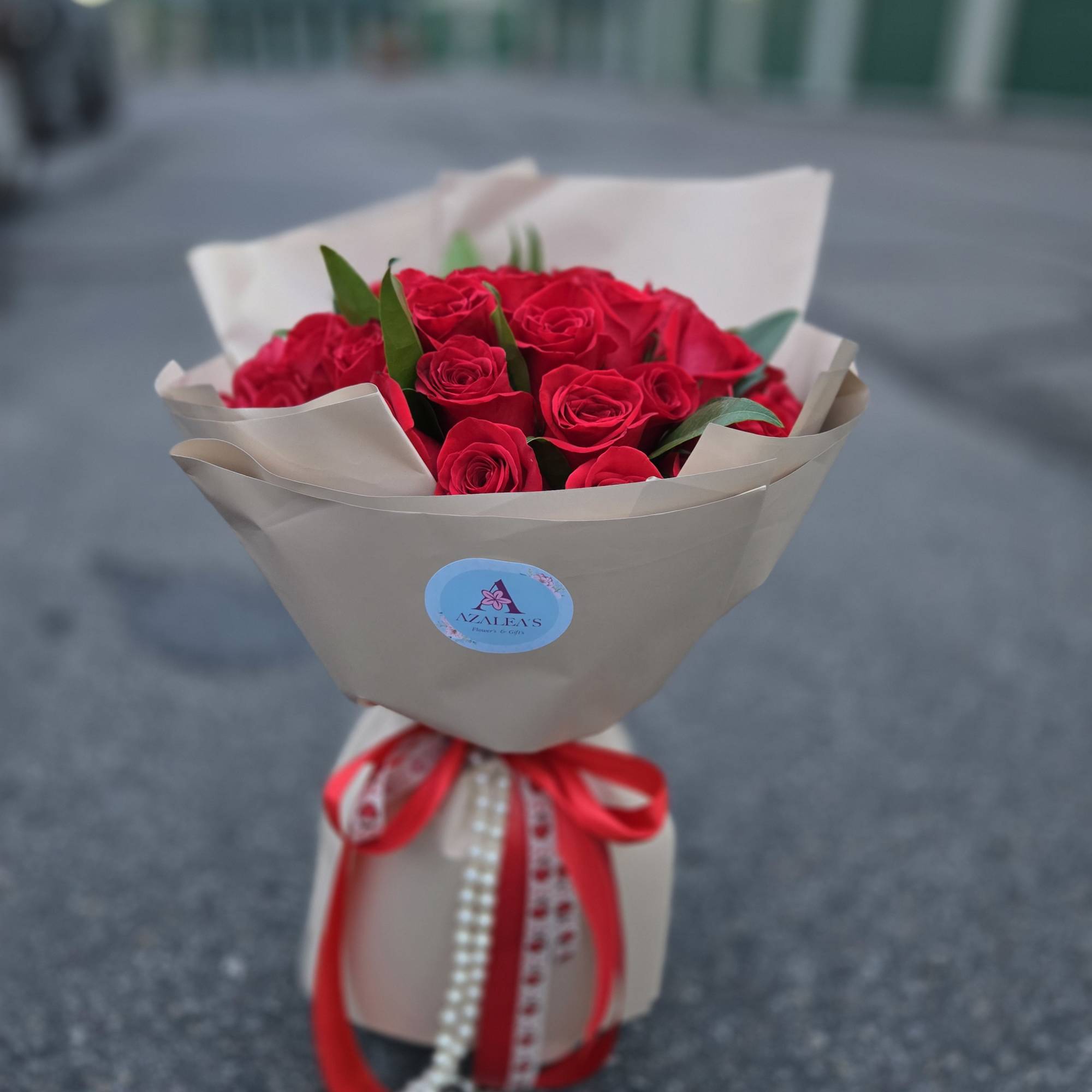 Bouquet of red roses wrapped in beige paper with a red ribbon