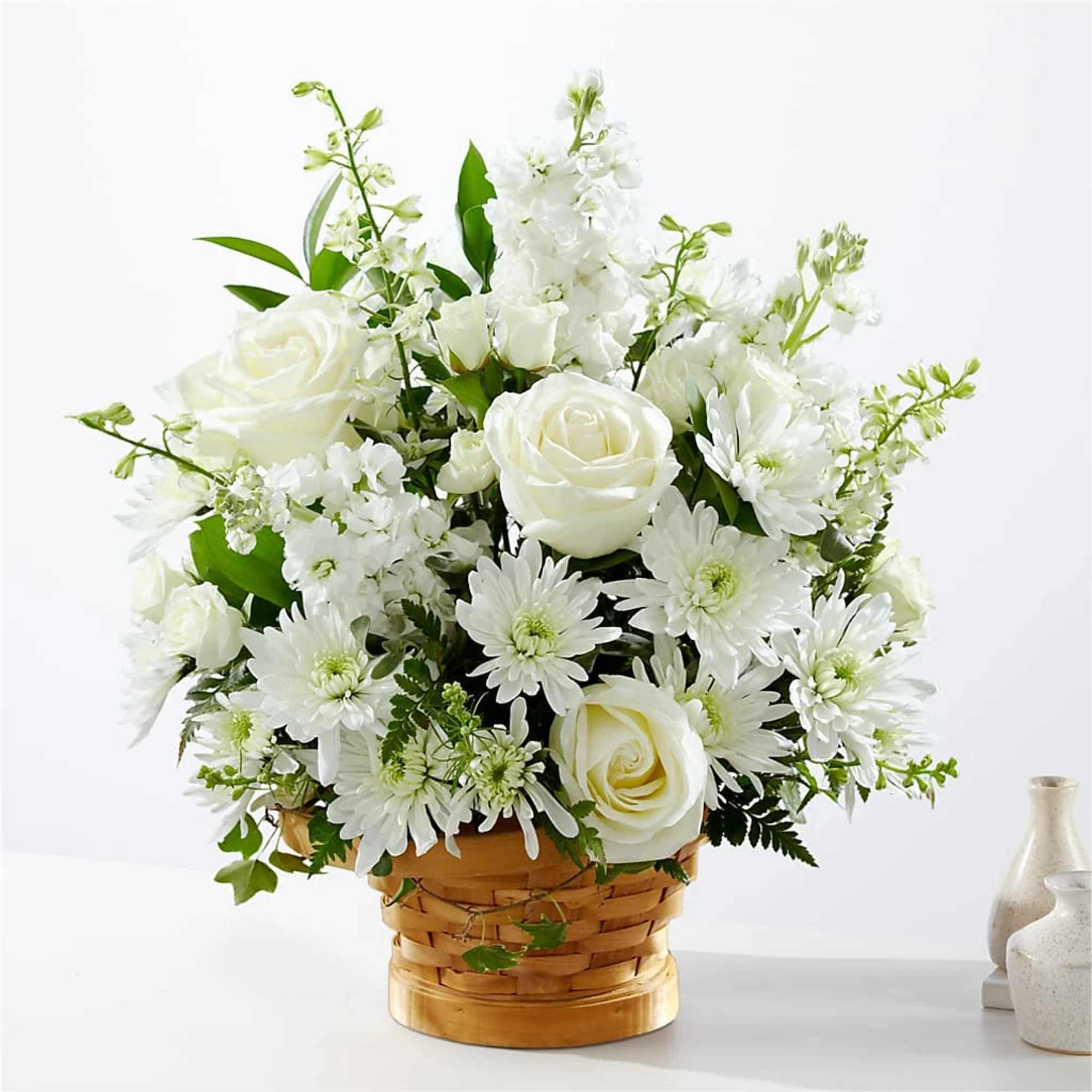 White roses and daisies arranged in a woven basket