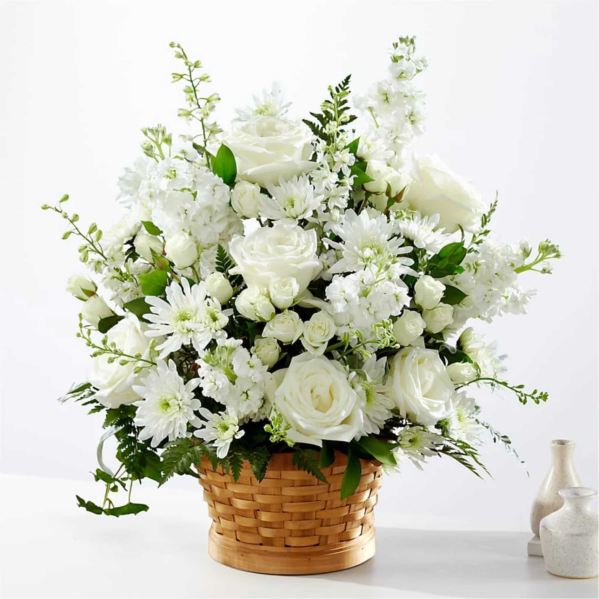 White roses and daisies arranged in a woven basket