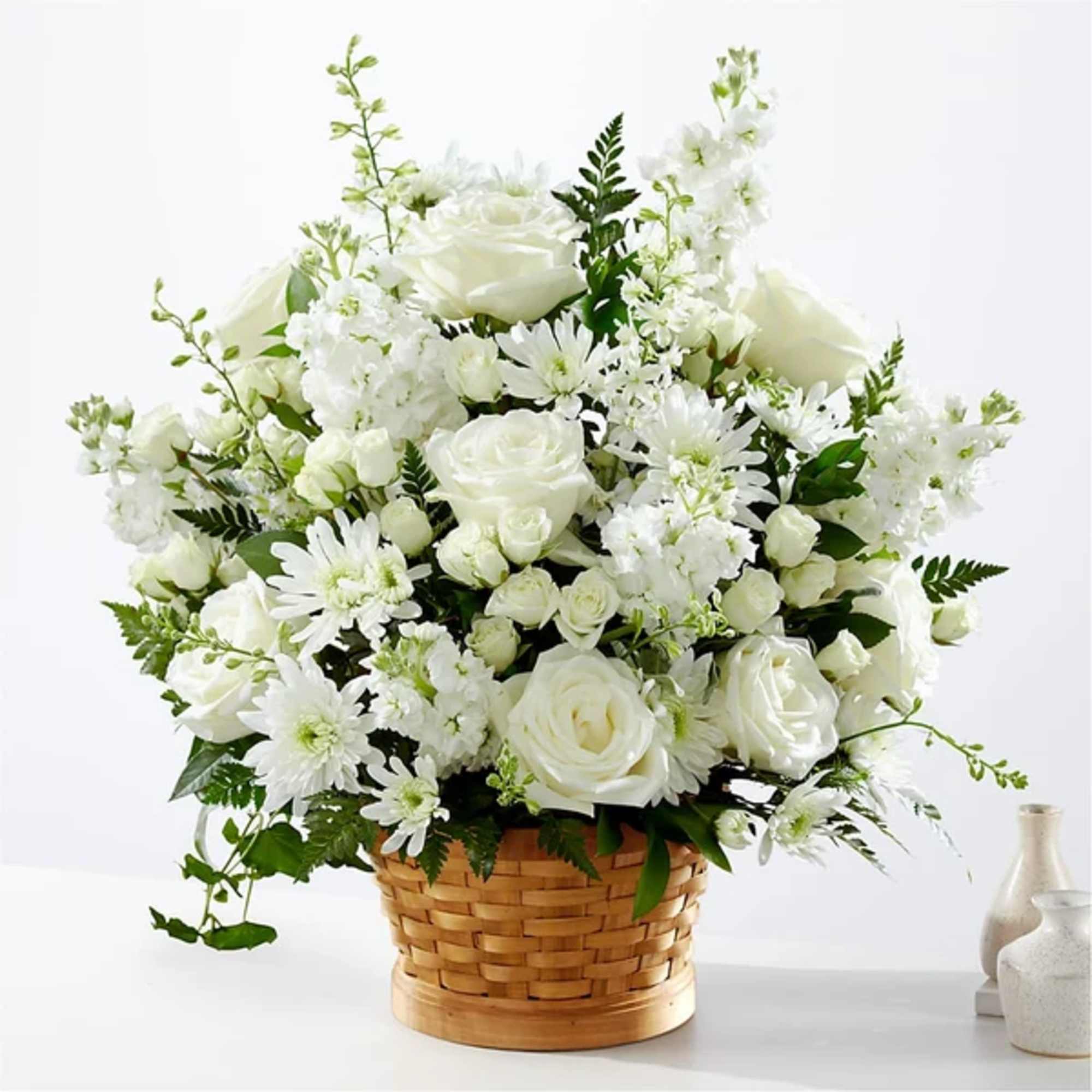 White roses and daisies arranged in a woven basket