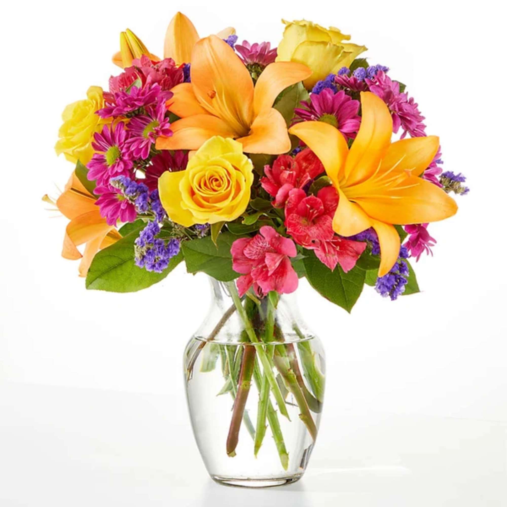 Colorful bouquet of lilies, roses, and daisies in a clear glass vase