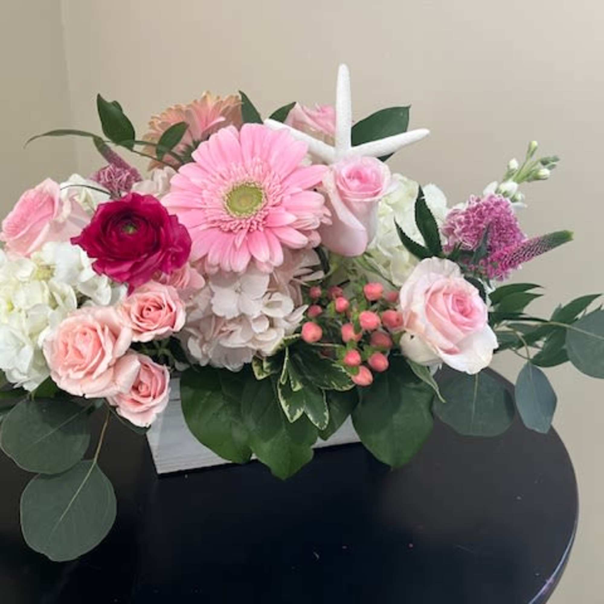 Low pink and white flower arrangement with gerbera daisy, roses, hydrangea and starfish pick in rectangular container