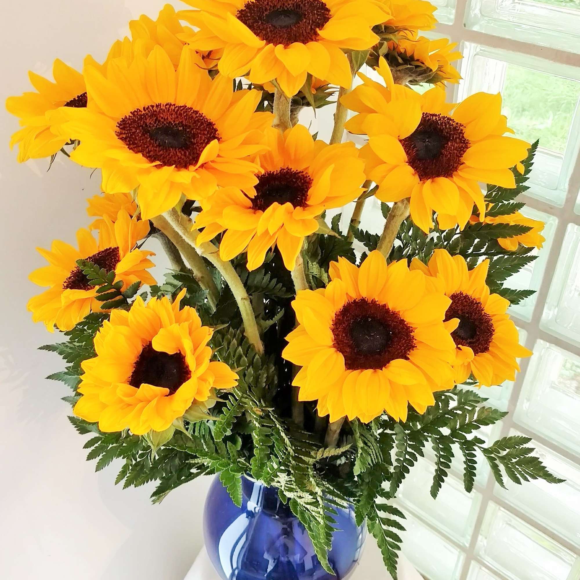 Bouquet of bright yellow sunflowers in a blue vase