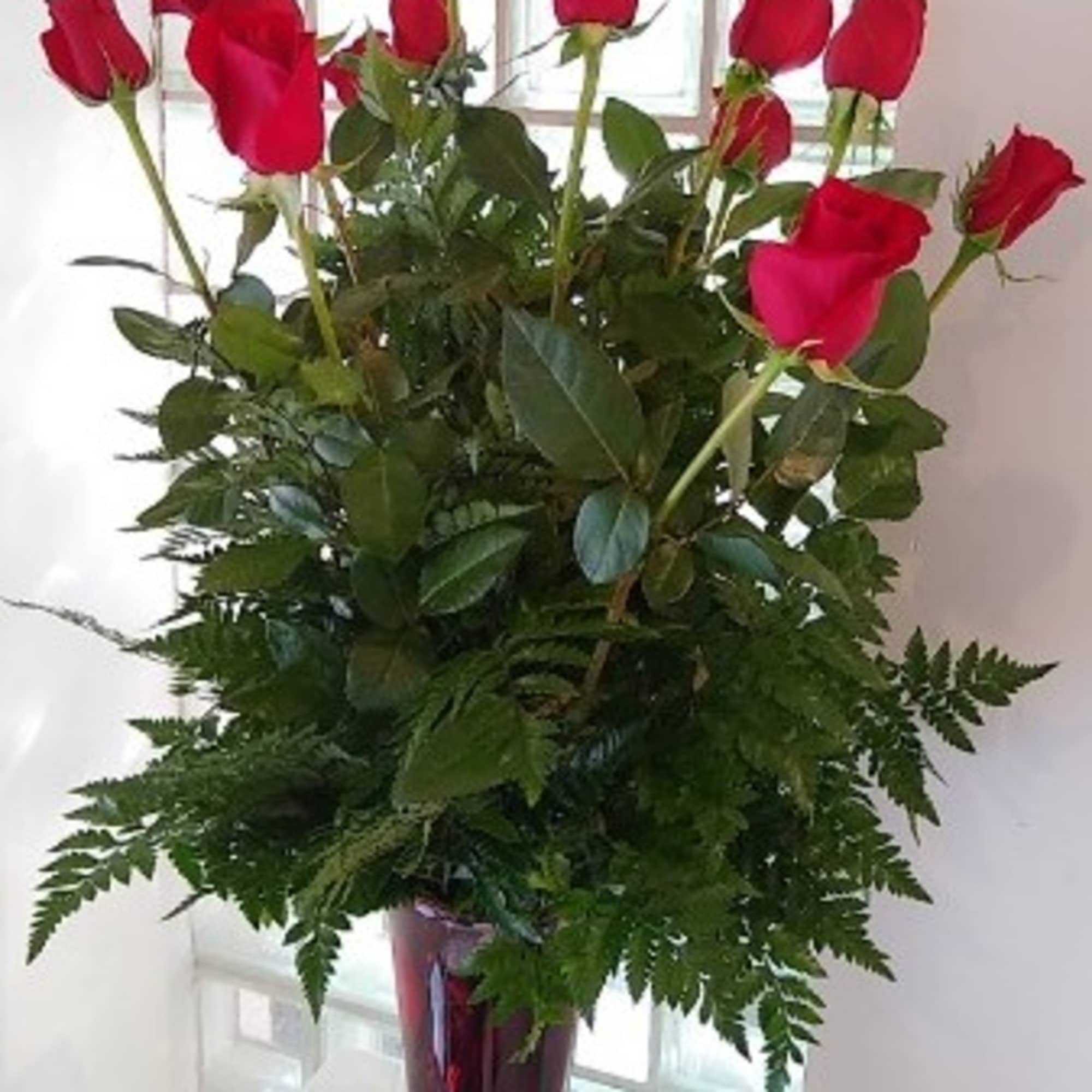Tall bouquet of red roses in a burgundy vase