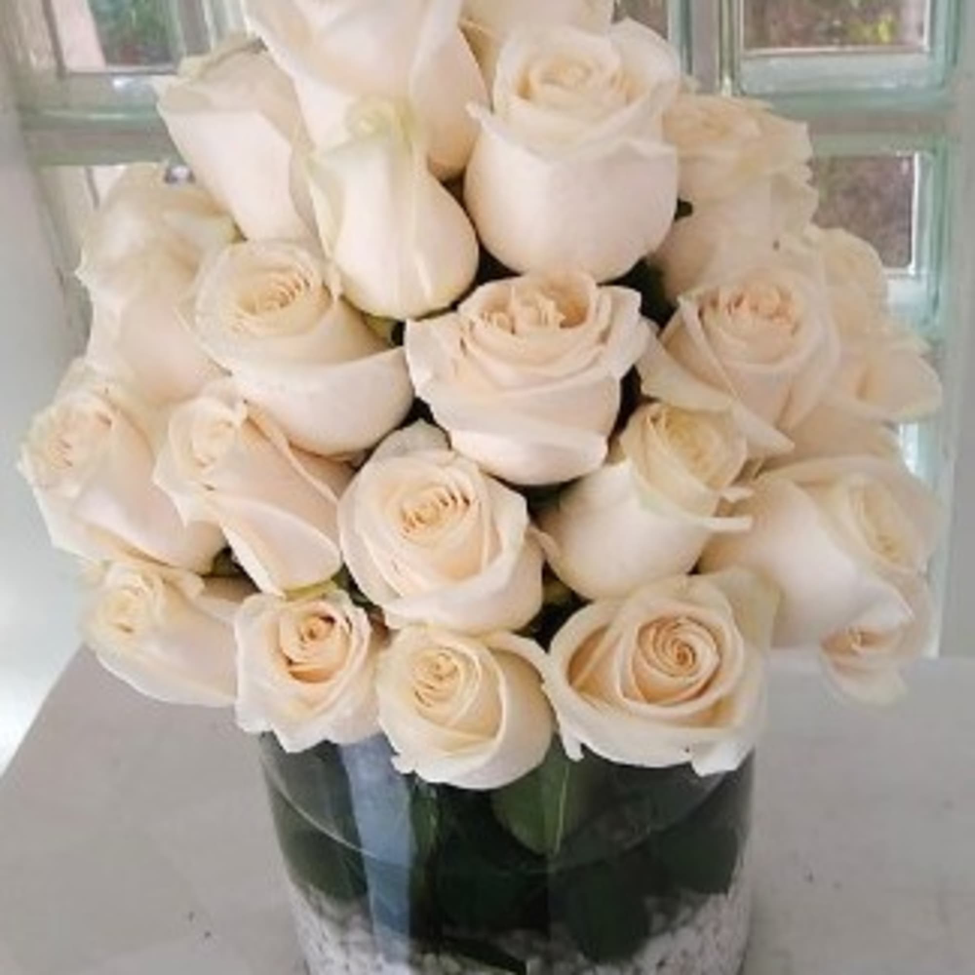 A dense cluster of pale cream roses arranged in a compact, domed