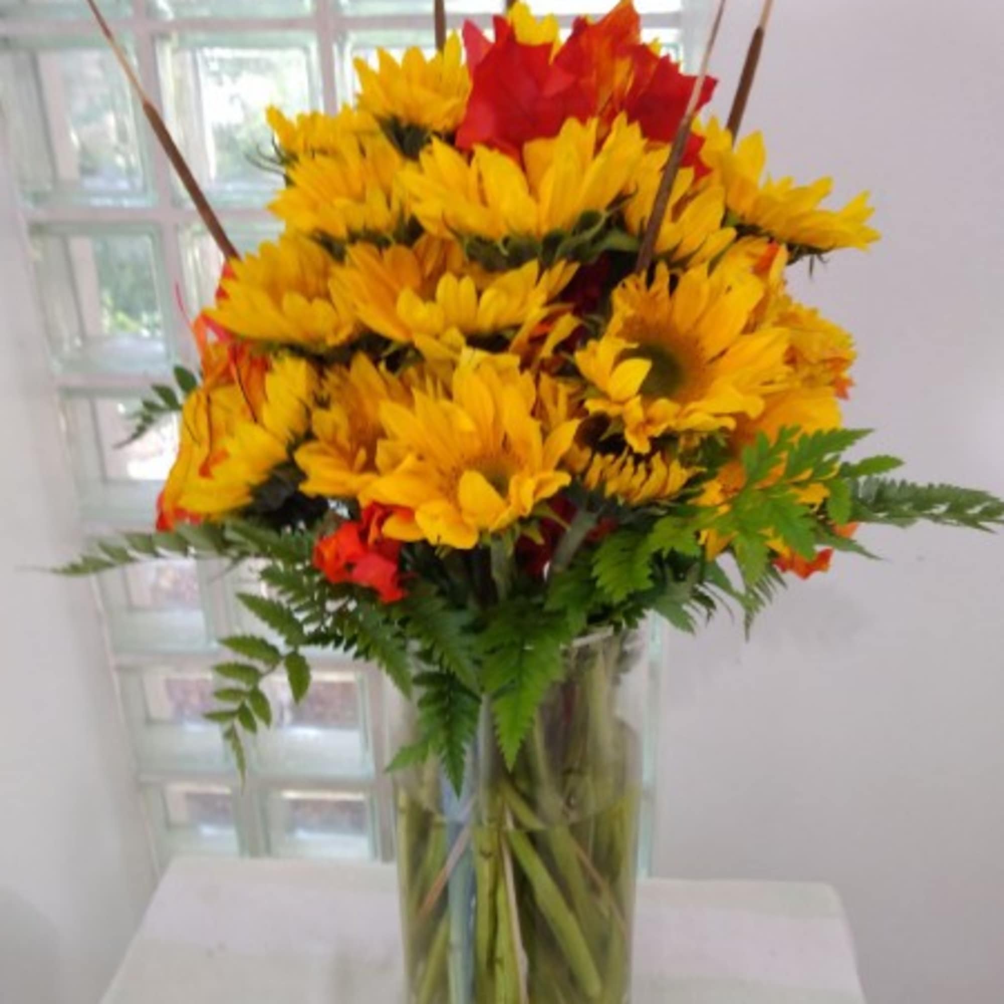 Yellow and red flowers arranged in a clear glass vase
