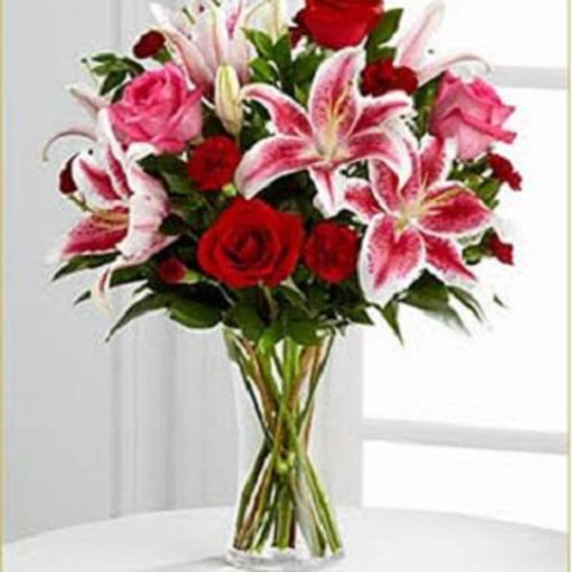Bouquet of red roses and pink lilies in a clear glass vase