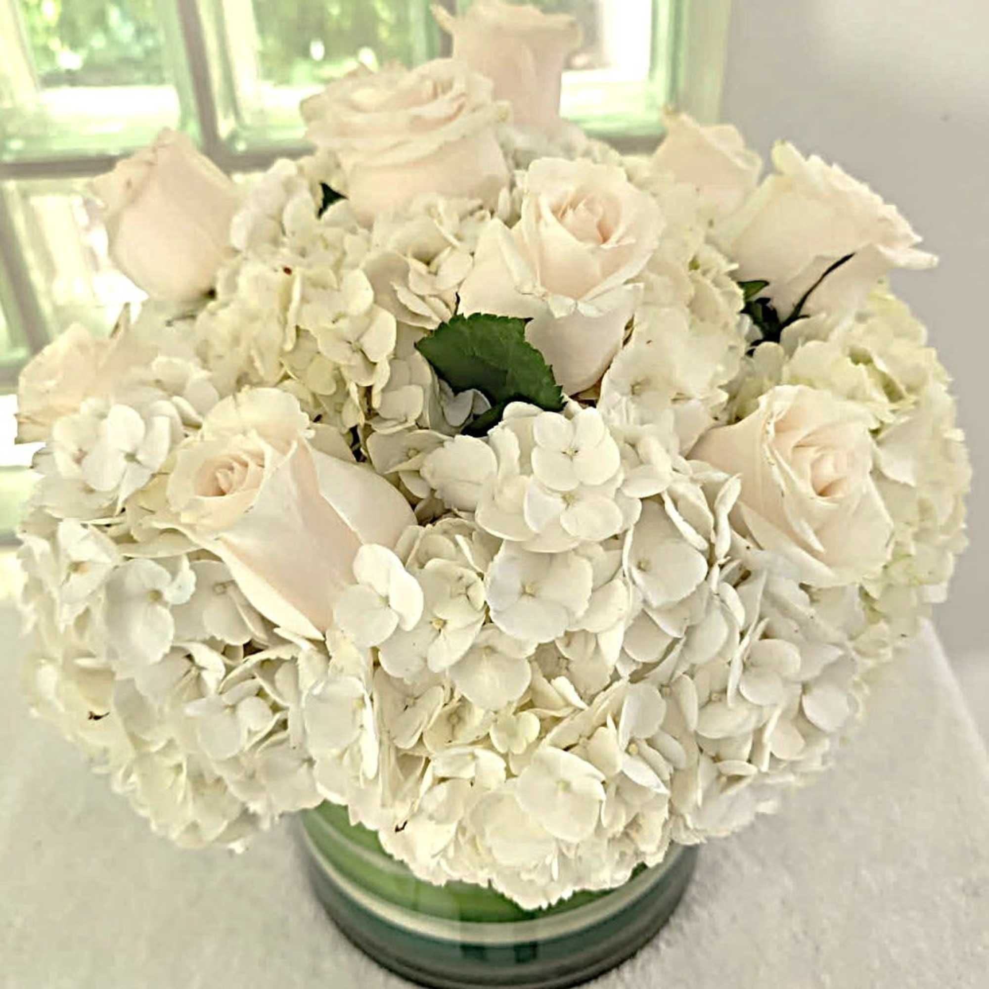 White roses and hydrangeas arranged in a glass vase