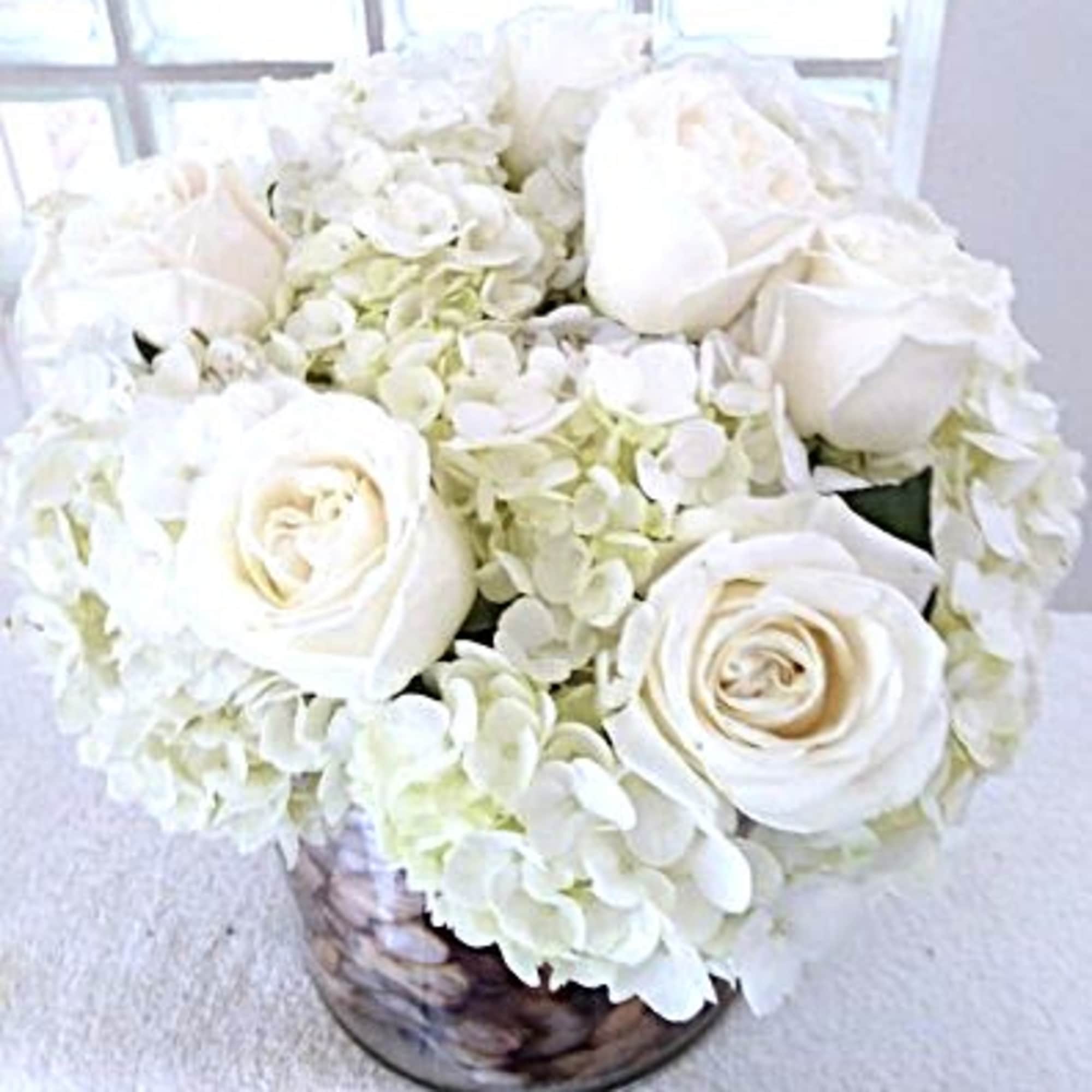 White roses and hydrangeas arranged in a glass vase