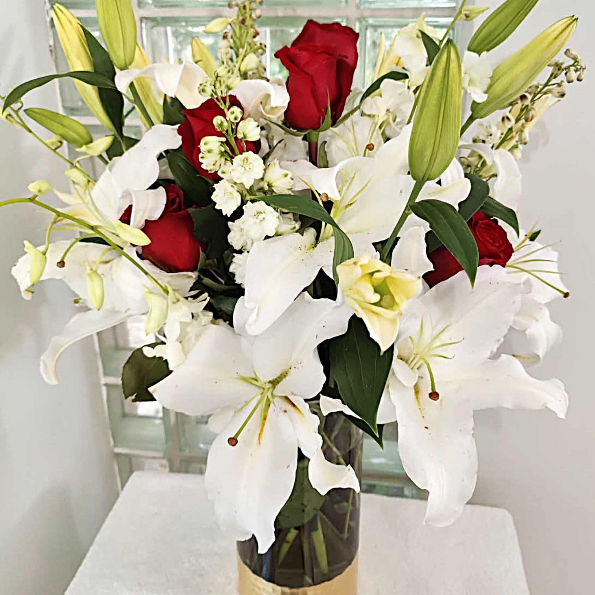 Red roses and white lilies arranged in a glass vase