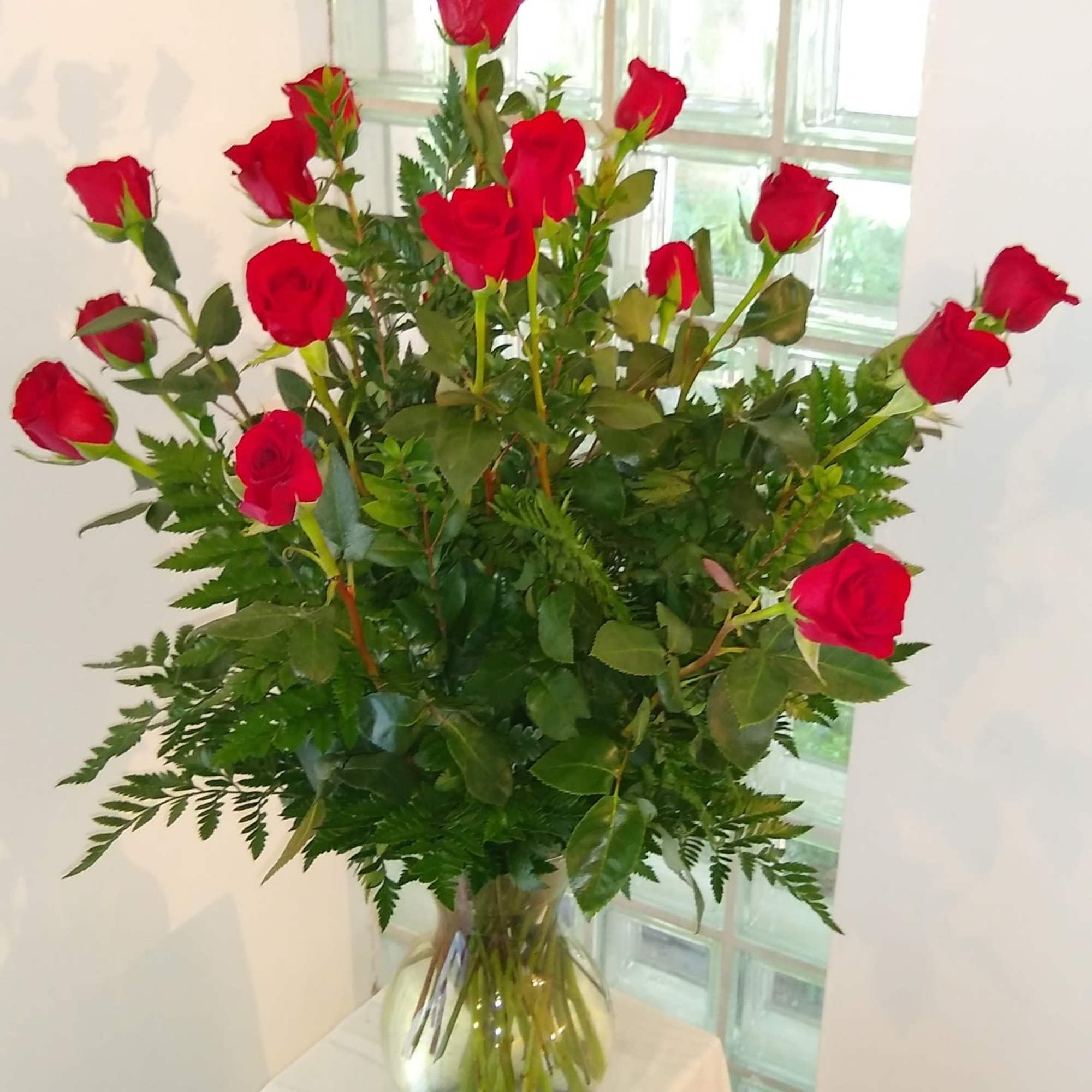 A symbol of lasting love. Arranged in a classic glass vase, this