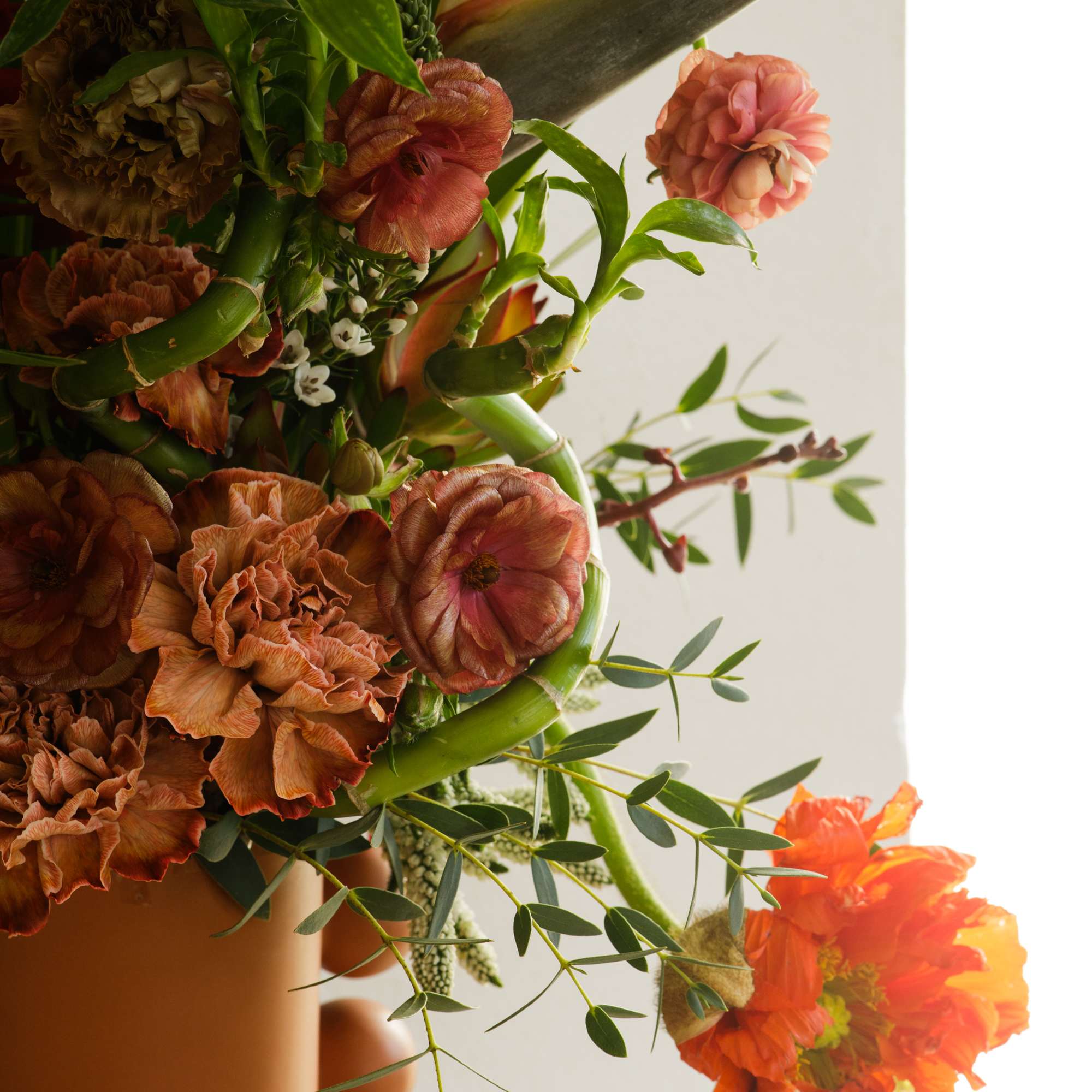 Orange and rust floral arrangement with tropical blooms in a vase