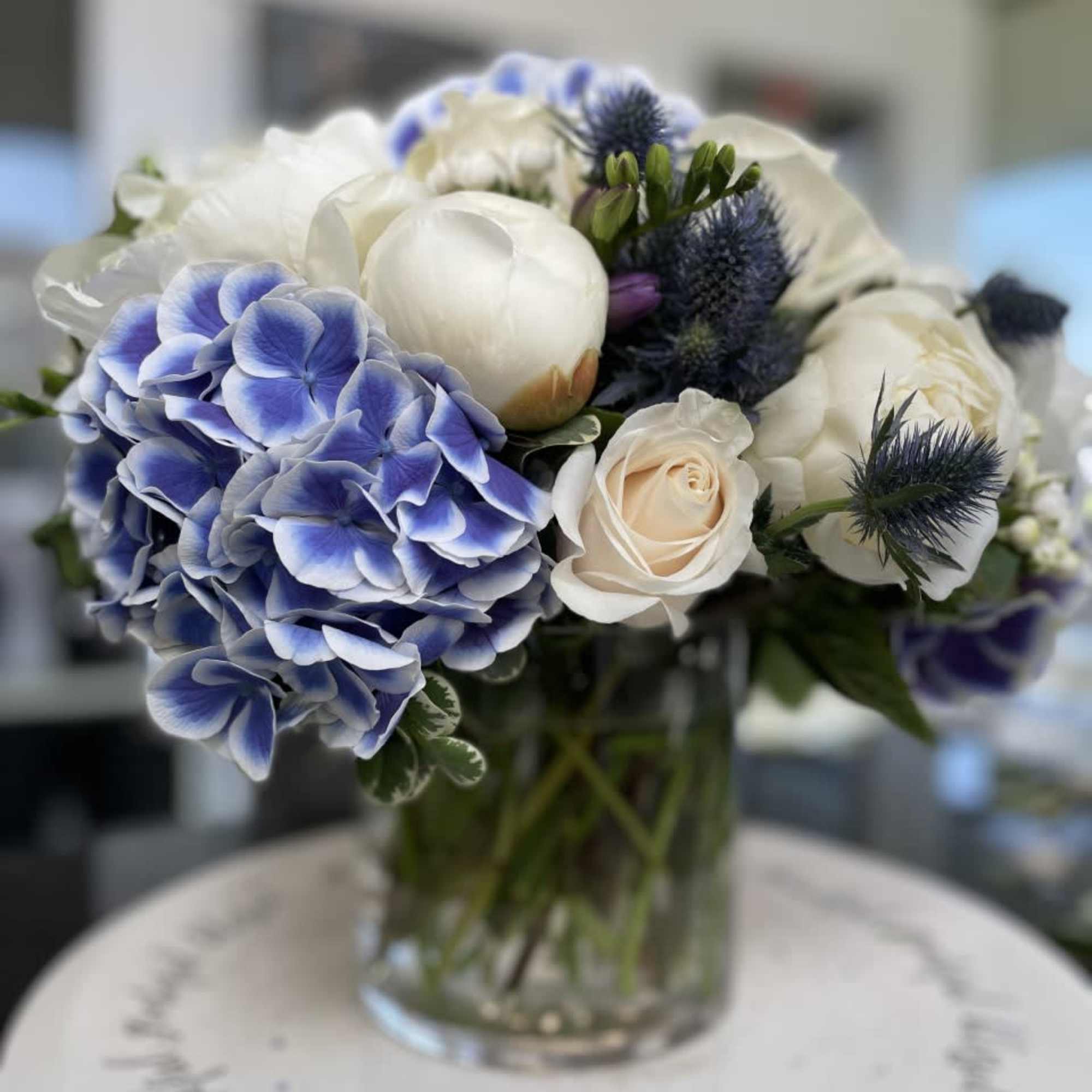 Blue hydrangeas and white roses arranged in a clear glass vase
