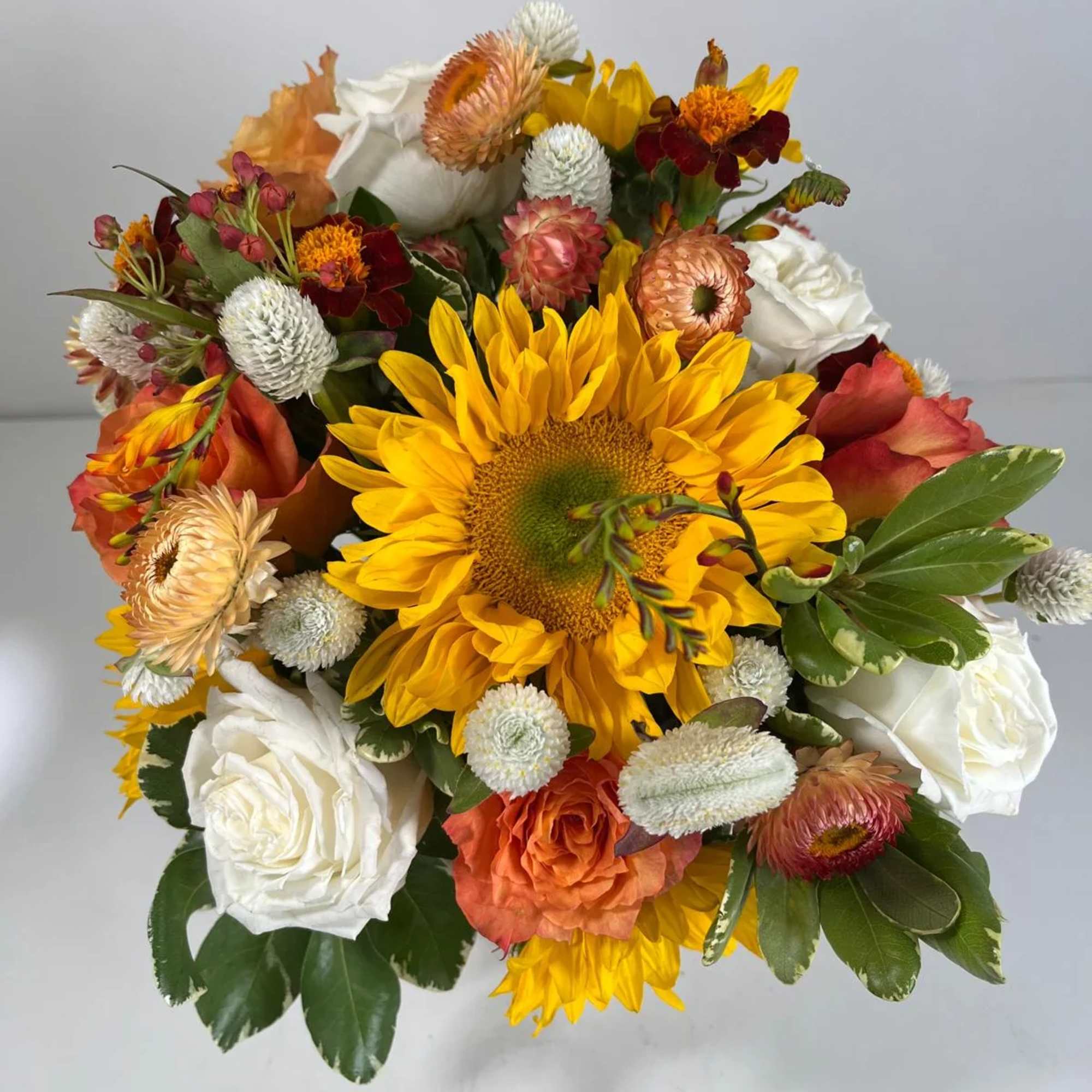 Bouquet with a large yellow sunflower, white roses, and orange blooms