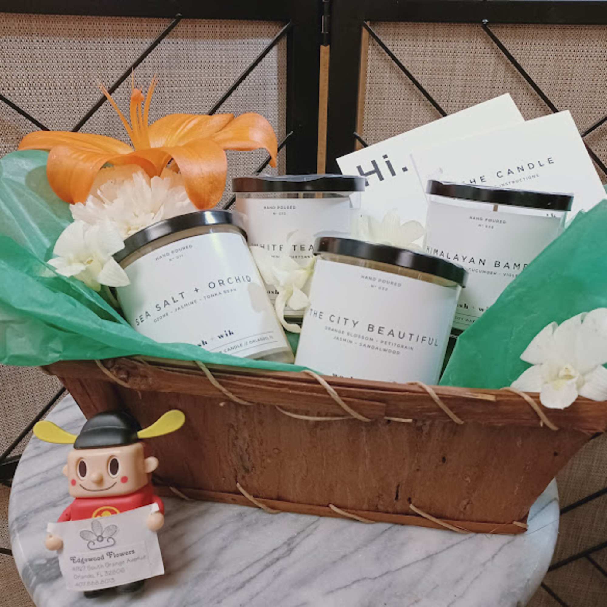 Gift basket with candles, white flowers, and a small figurine