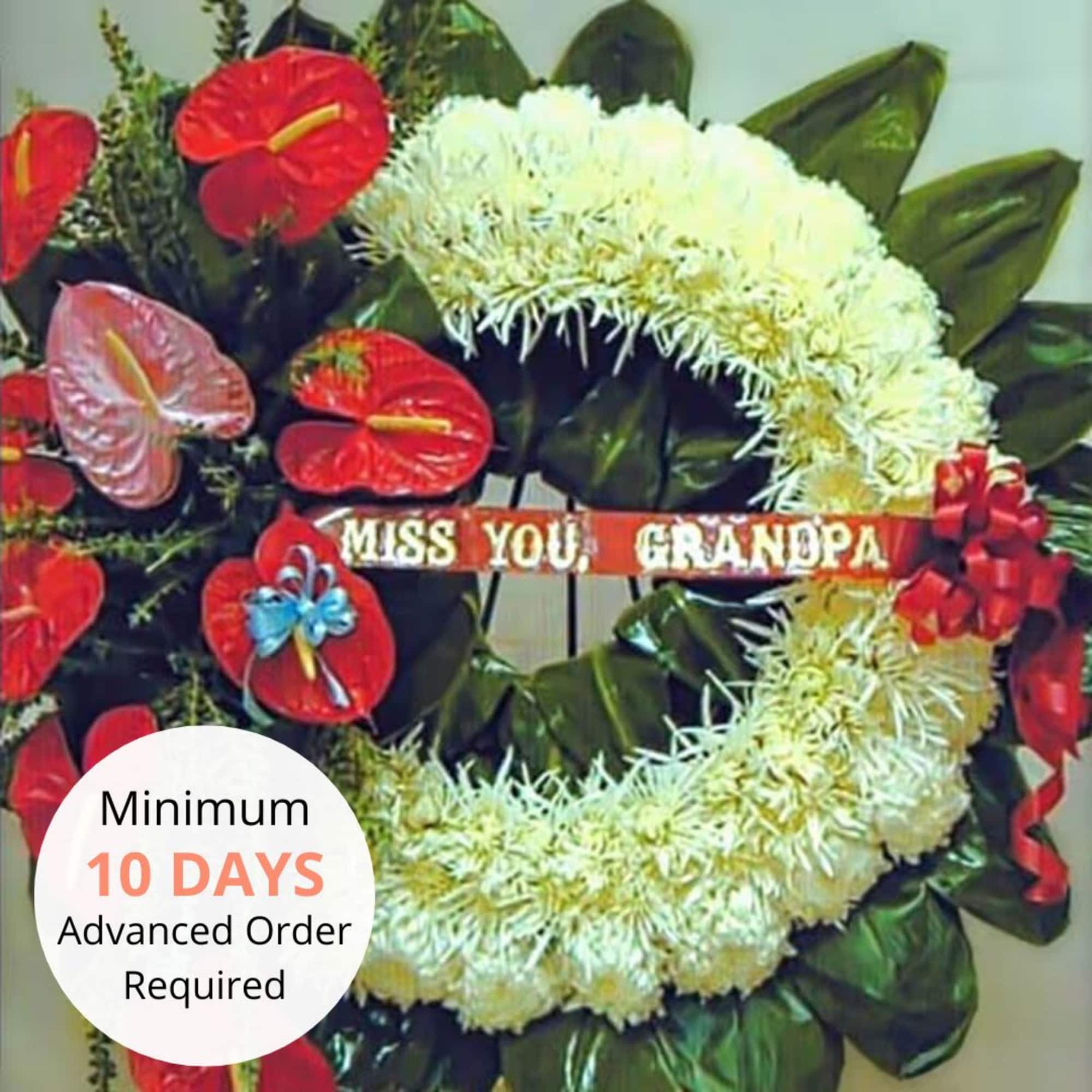Round white chrysanthemum funeral wreath with red tropical flowers and a 'Miss You, Grandpa' banner