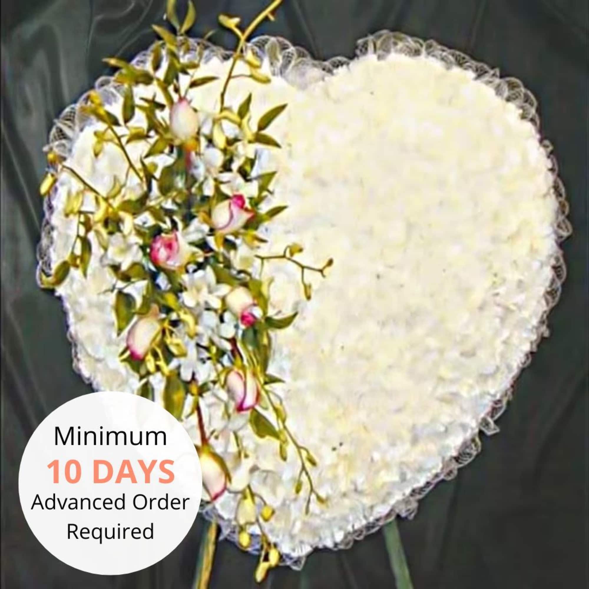 Heart-shaped white floral tribute with pink rose spray on one side
