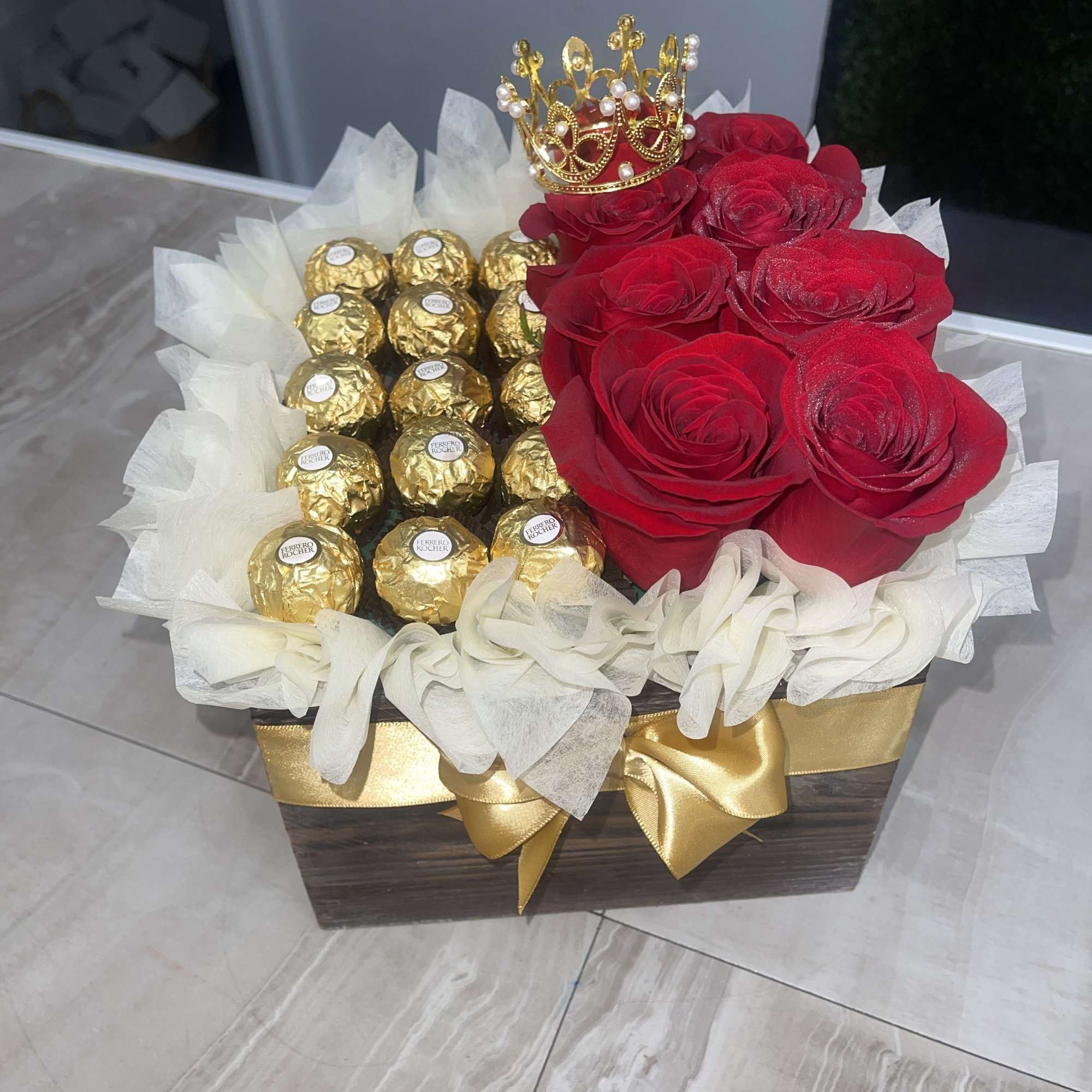 A cluster of deep red roses paired with gold-wrapped chocolates makes a
