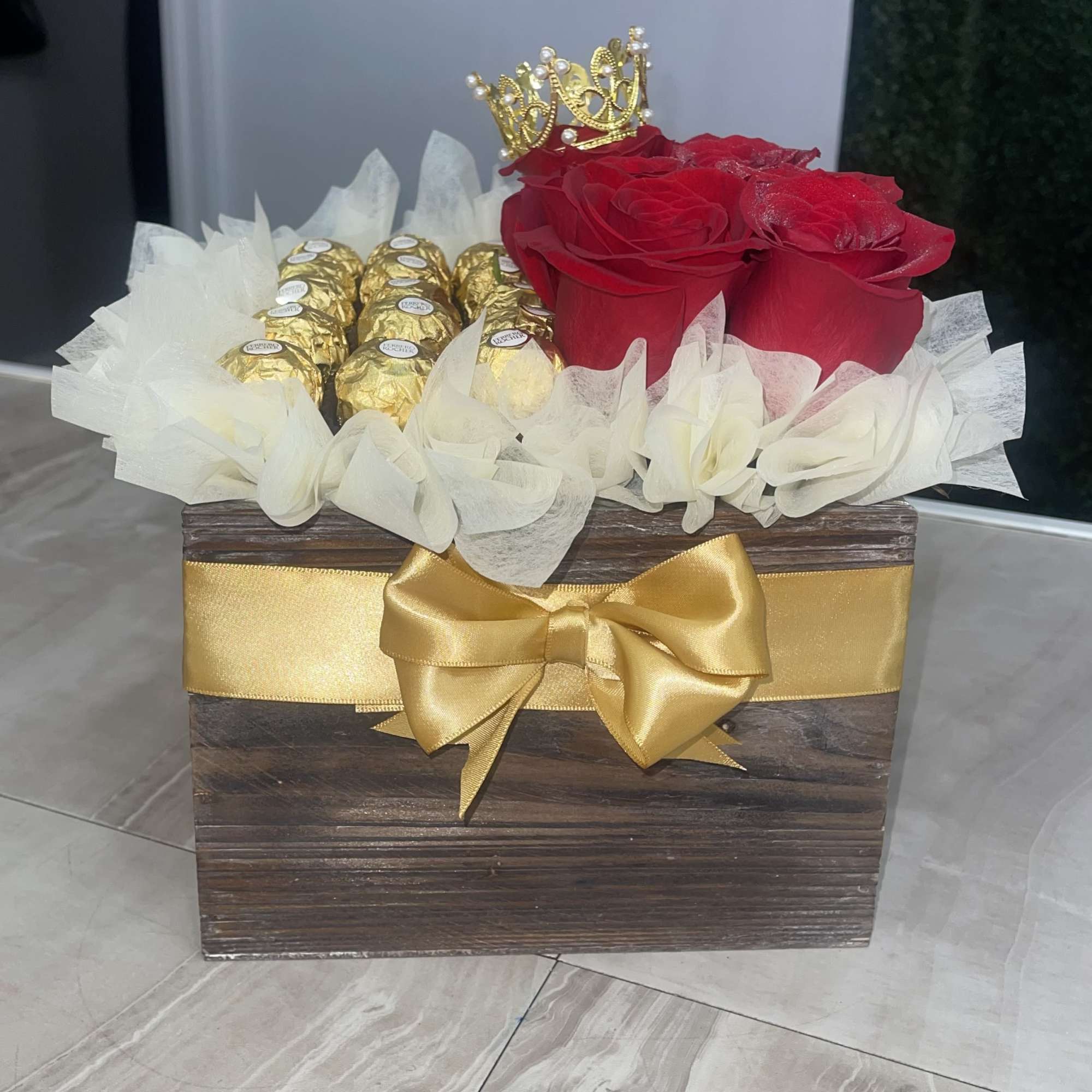 A cluster of deep red roses paired with gold-wrapped chocolates makes a