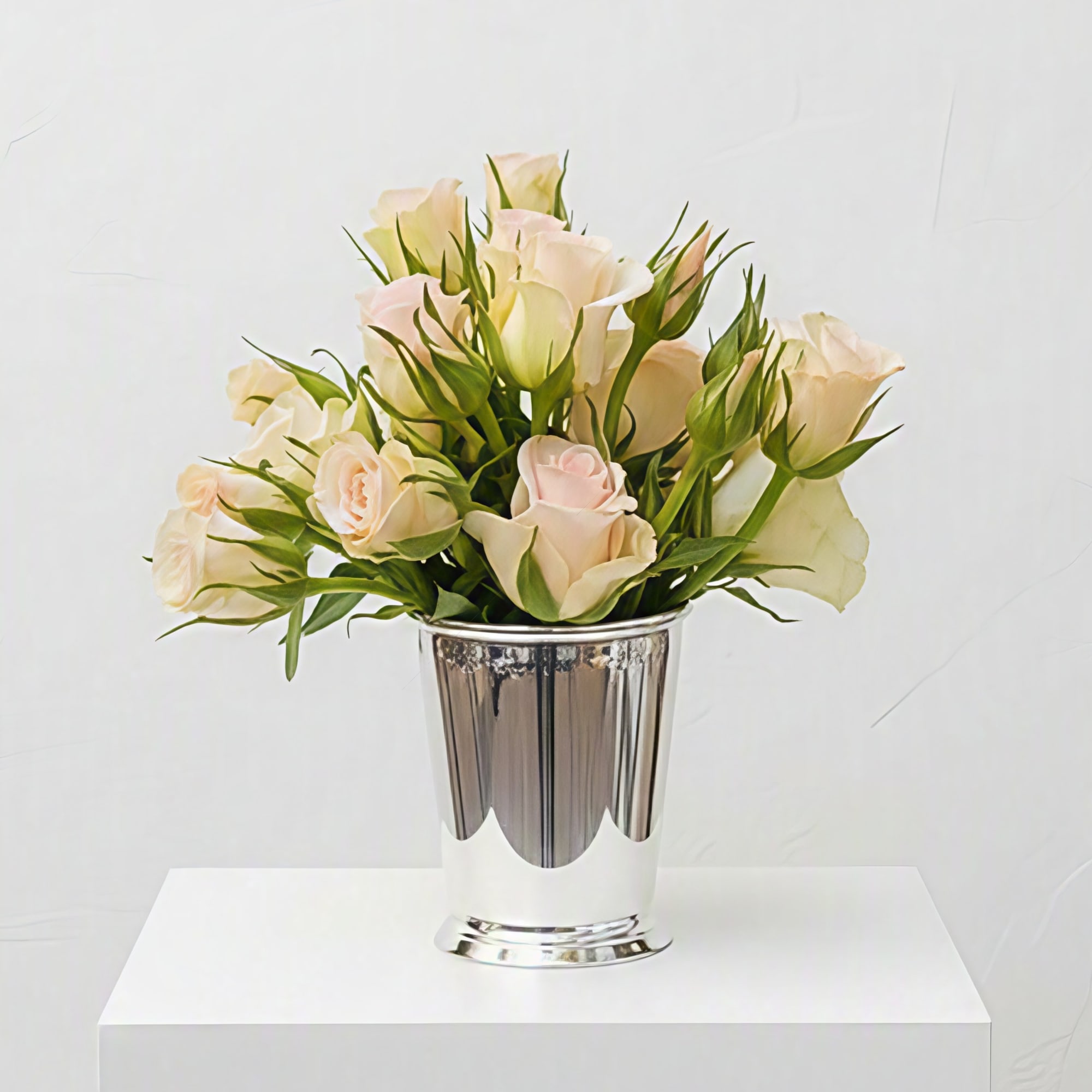 Pale pink and cream roses arranged in a silver vase