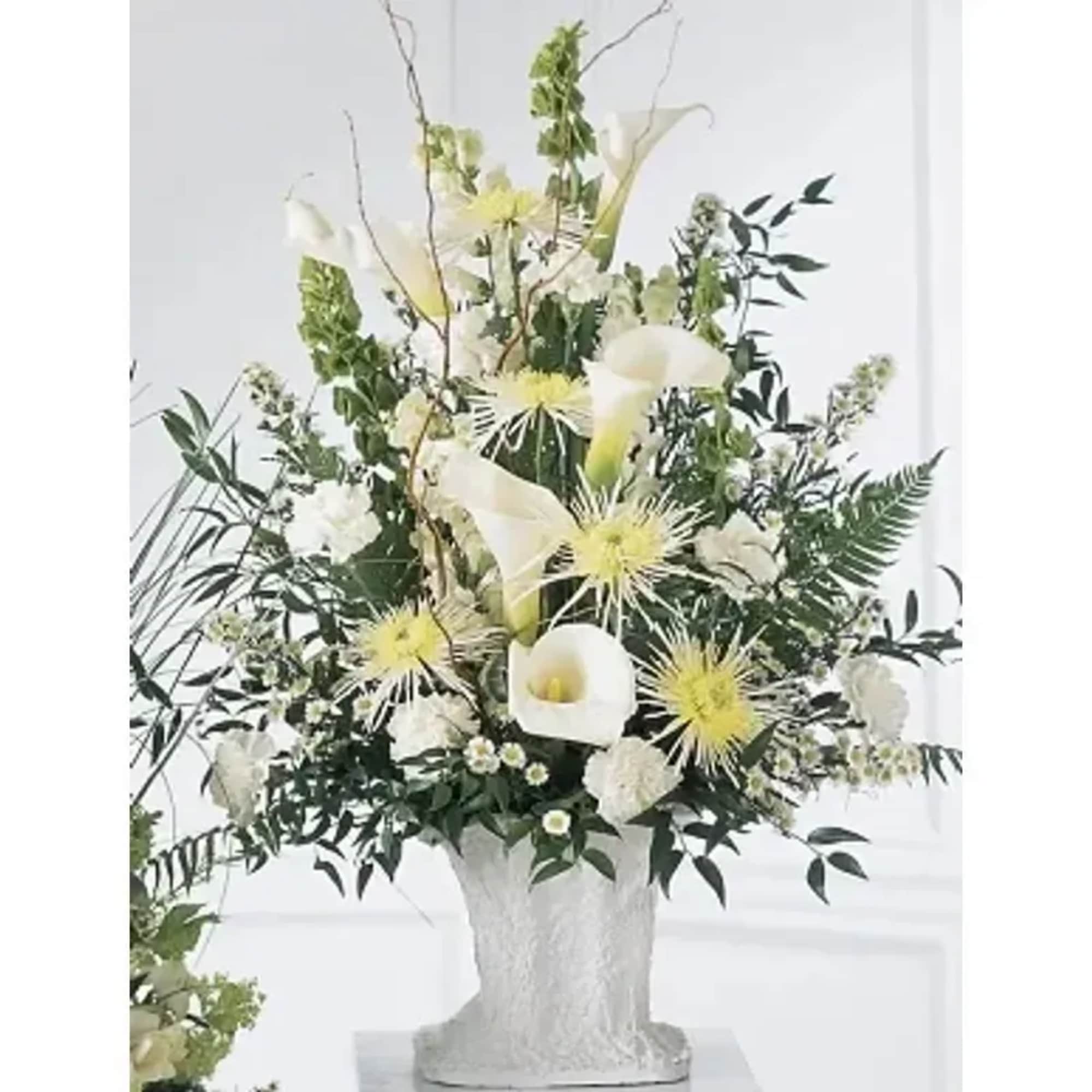 A traditional sympathy arrangement in white. This elegant arrangement features white calla