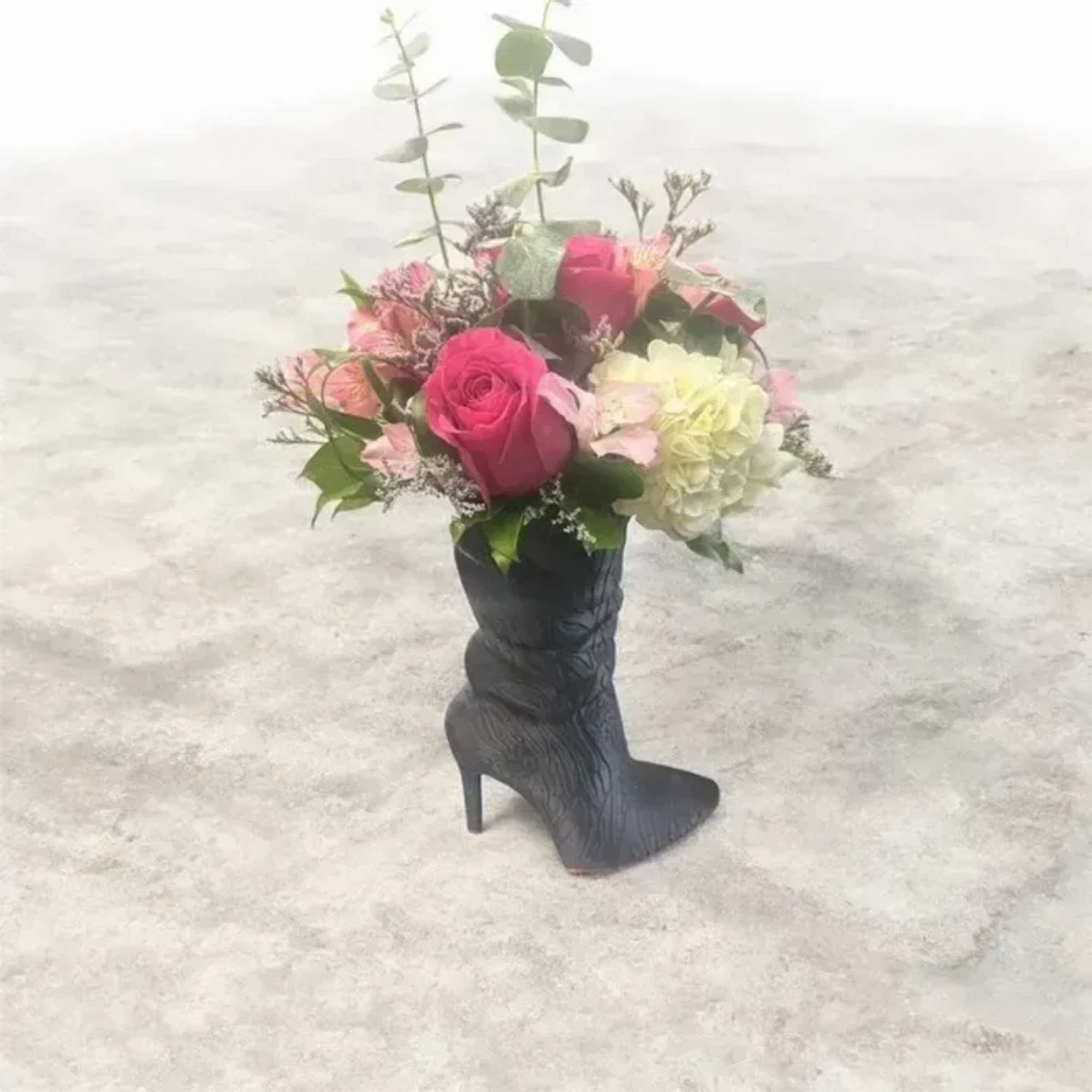 A bright pink rose takes center stage in this fashion-forward flower arrangement